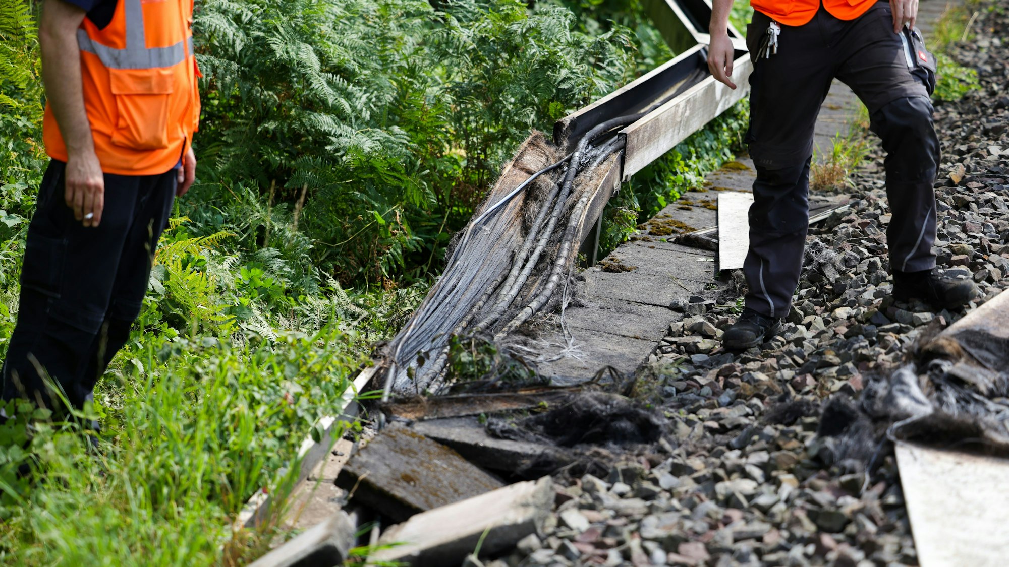 Mitarbeiter der Deutschen Bahn arbeiten an einem Gleisabschnitt in Düsseldorf. Dort wurde neben der Bahnstrecke Feuer in einem Kabeltunnel gelegt, der sechs Kabel in Mitleidenschaft zog. Foto: Christoph Reichwein/dpa