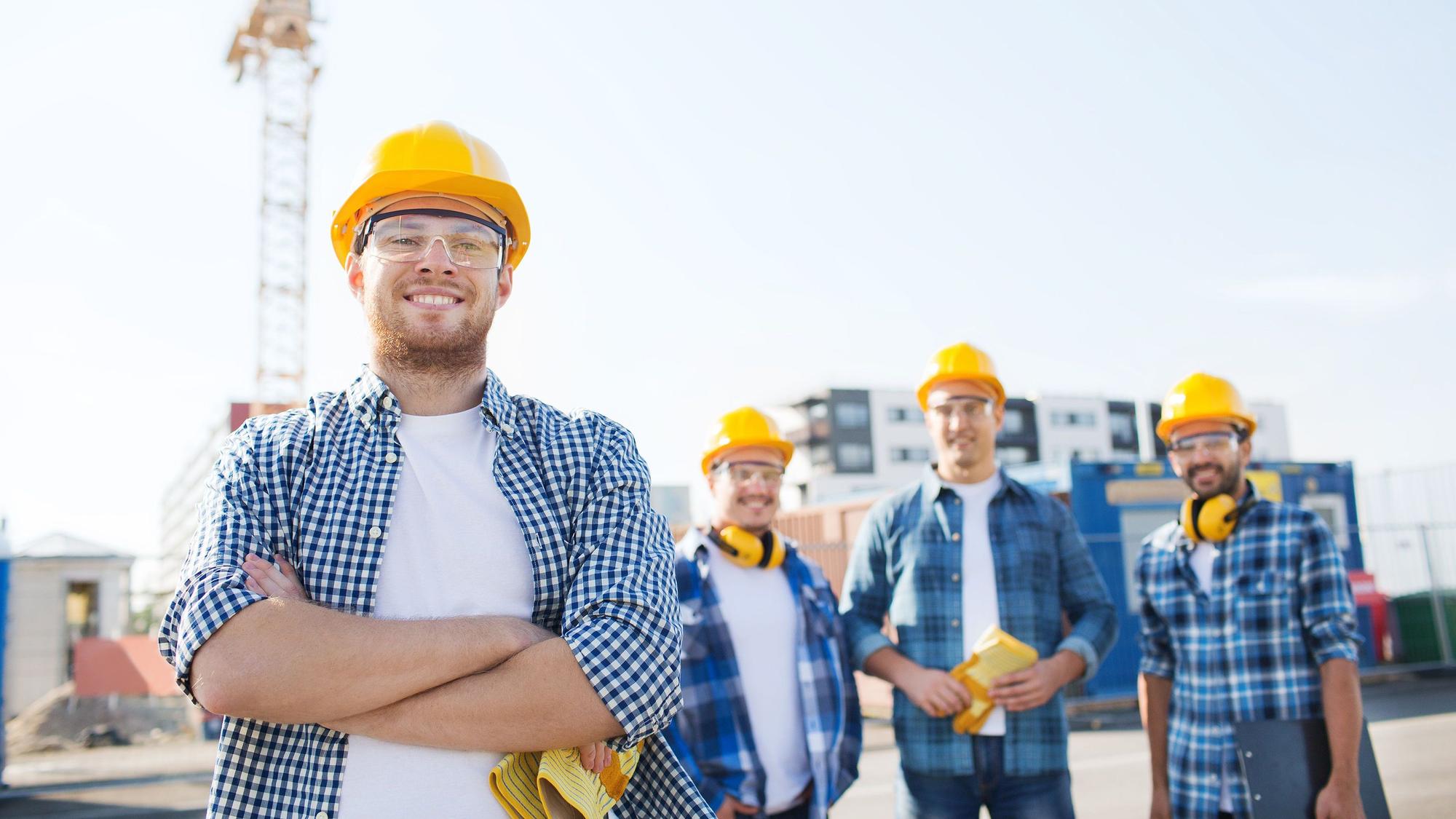 Eine Gruppe junger Handwerker steht auf einer Baustelle.