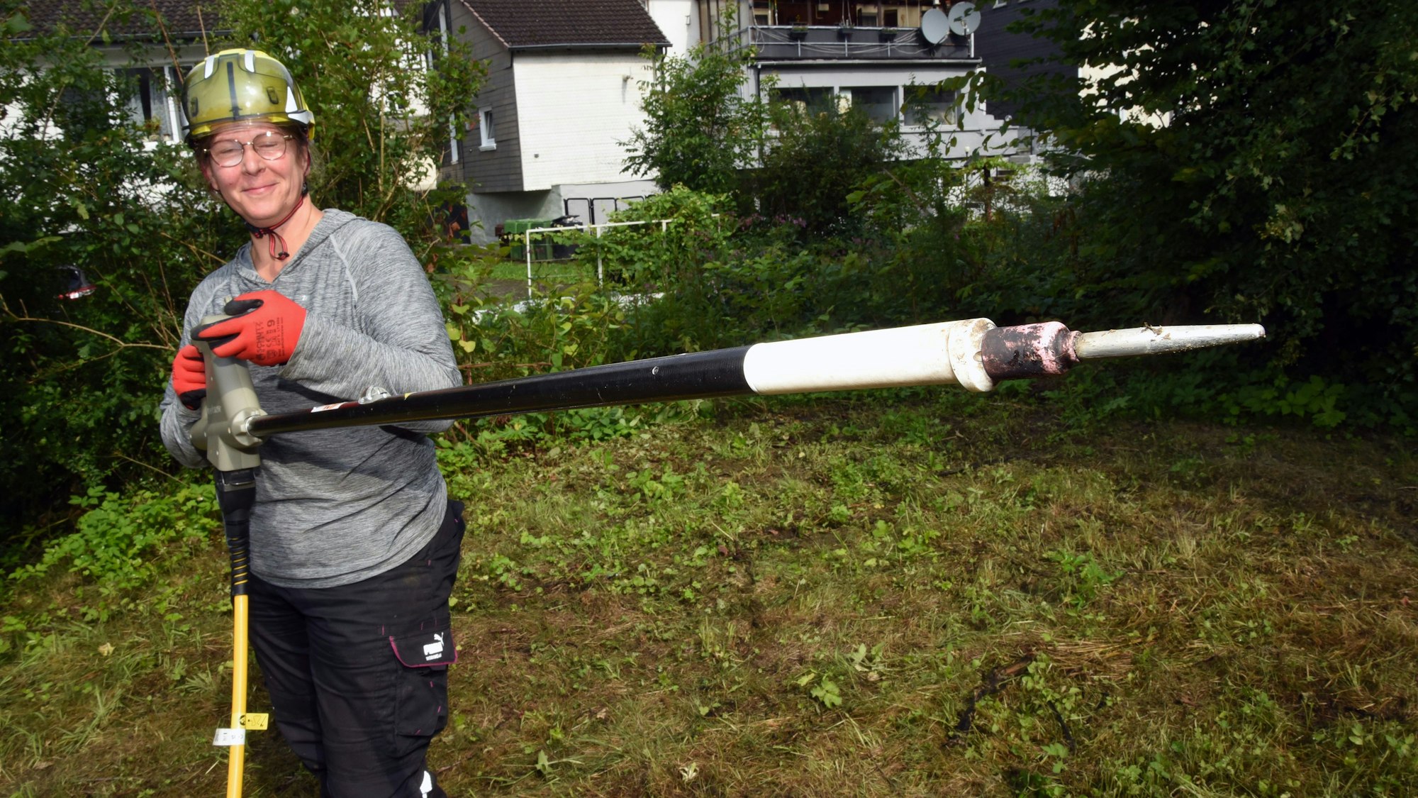 Eine Frau mit einem Rootwave, einem elektrischen Gerät zur Pflanzenbekämpfung, in der Hand.