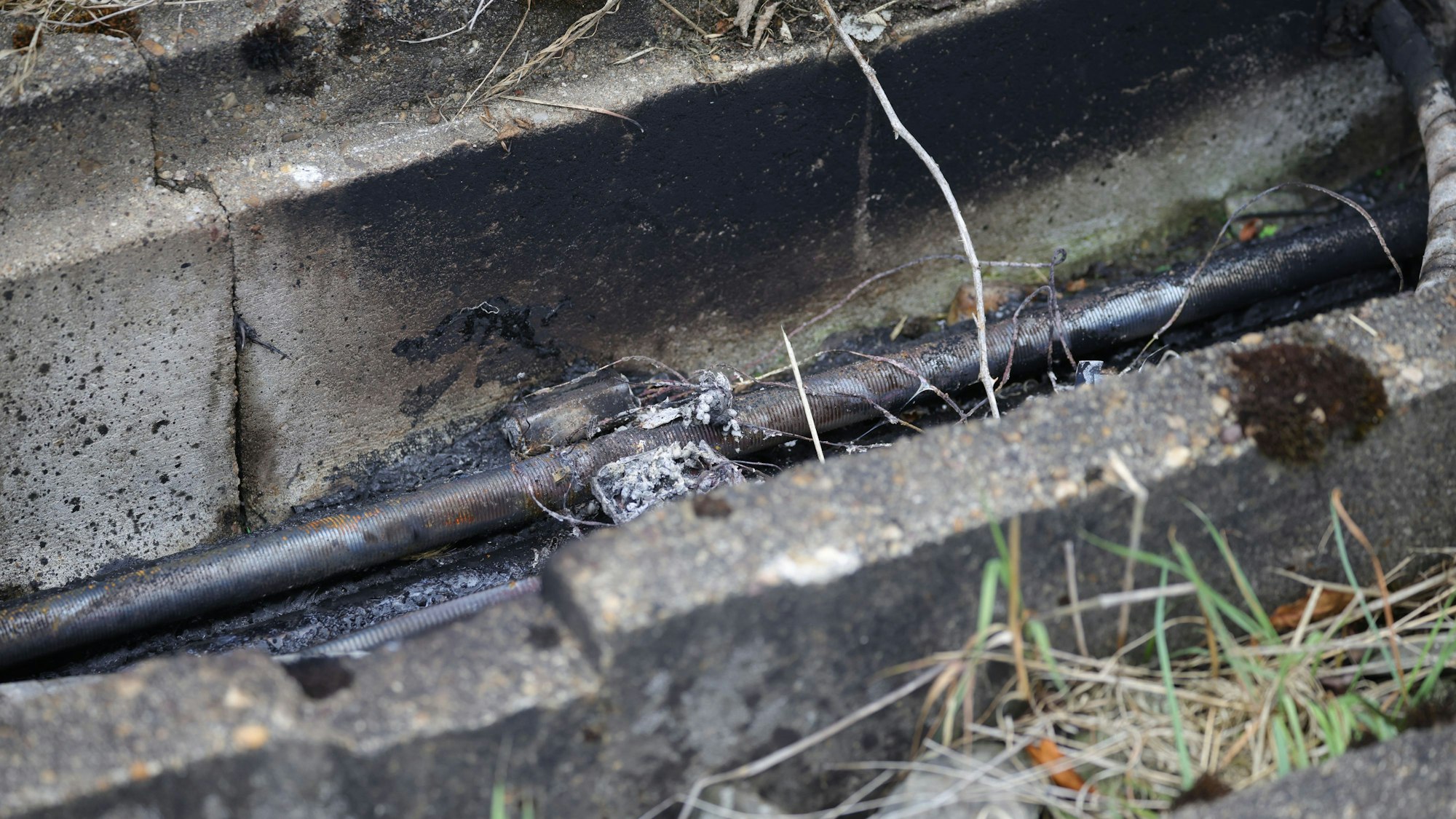 Brandspuren sind am Rande von Gleisen in einem Betontrog zu sehen - darin verlaufen Kabel. Auf die wichtige Nord-Süd-Strecke der Deutschen Bahn ist ein weiterer Brandanschlag verübt worden.