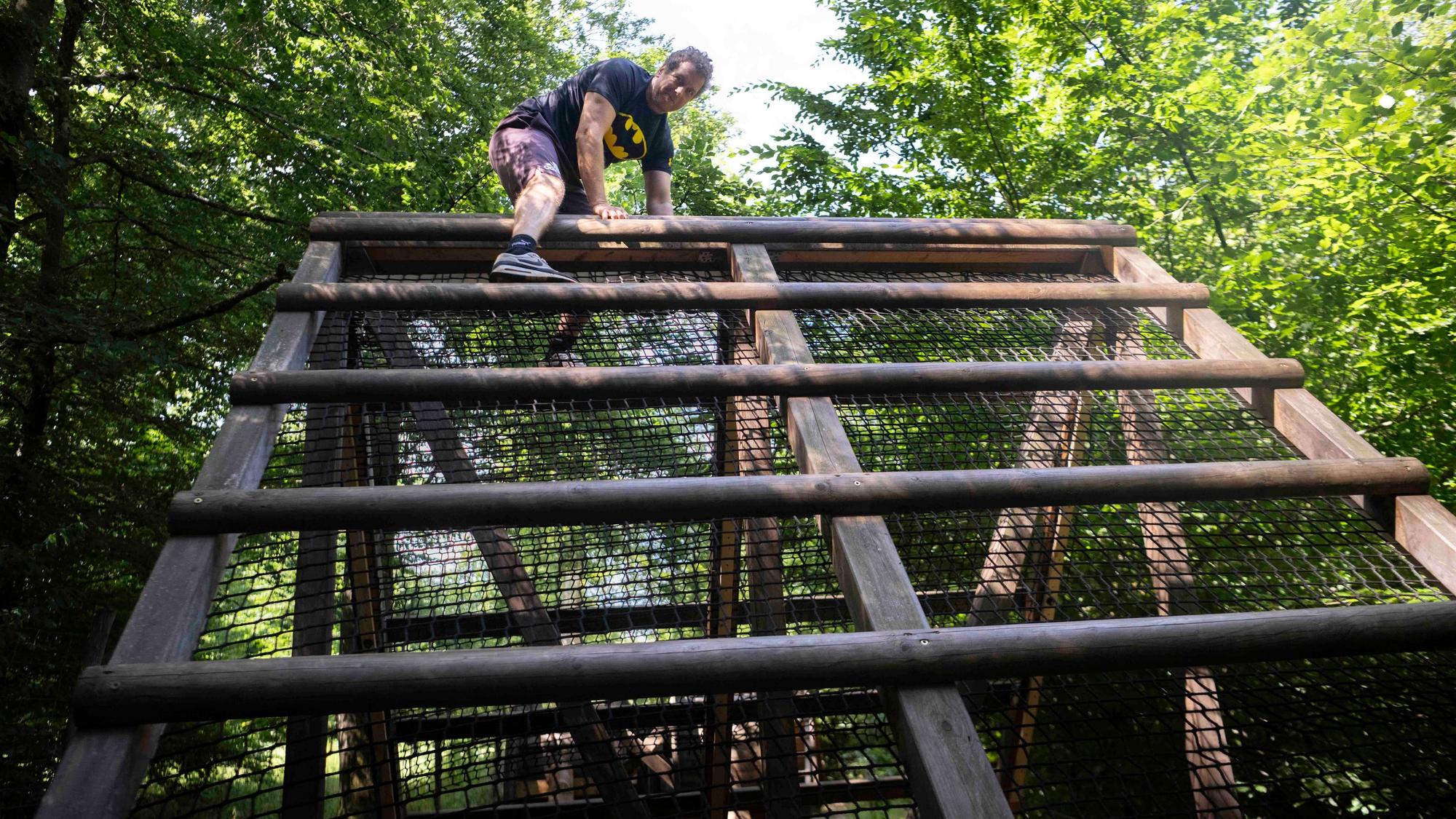Ein Mann klettert im Arboretum in Nettersheim über ein Hindernis.
