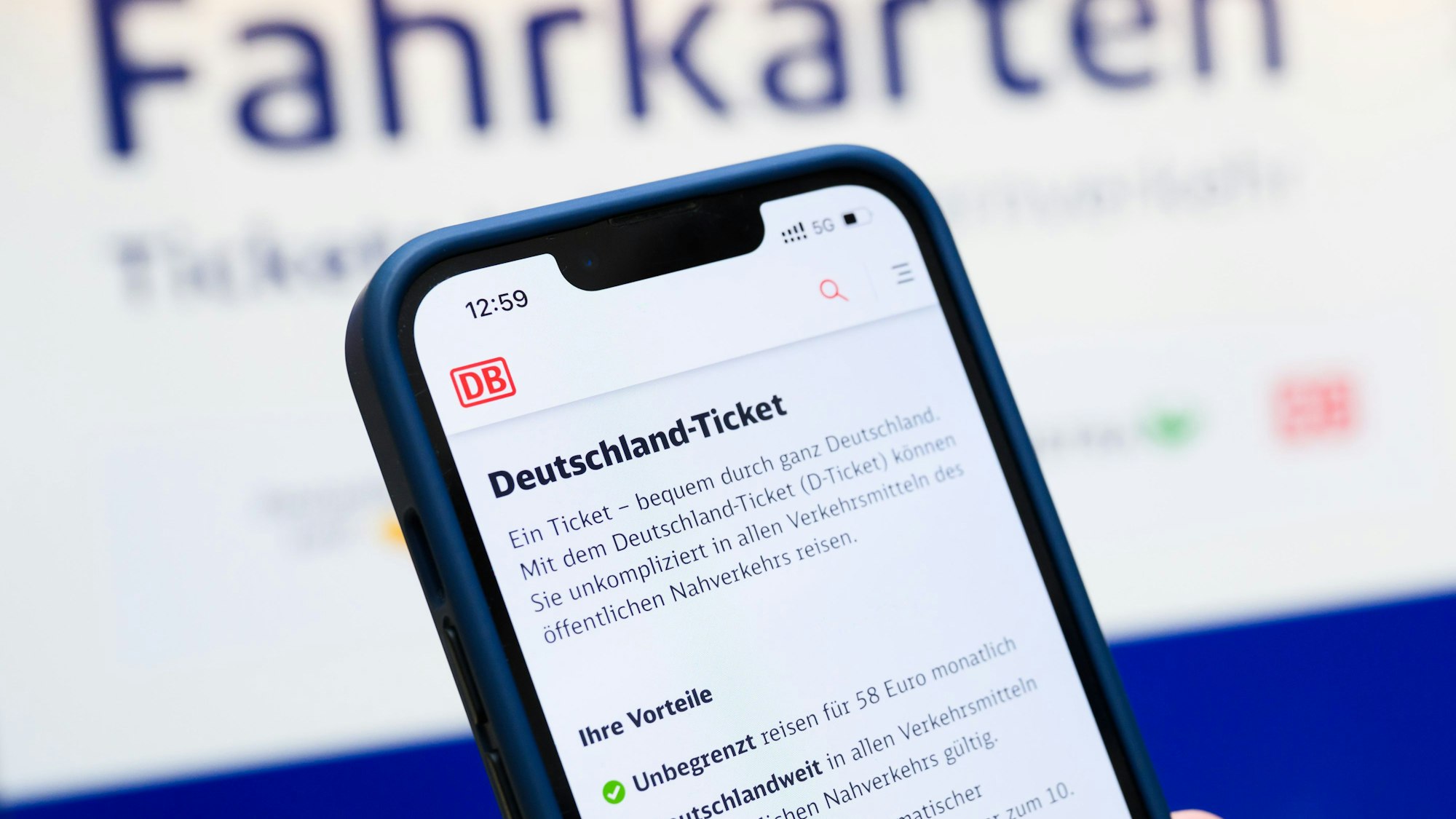 Eine Person hält am Hauptbahnhof ein Smartphone in der Hand, auf dessen Display eine Information zum Kauf des Deutschlandtickets zu sehen ist.
