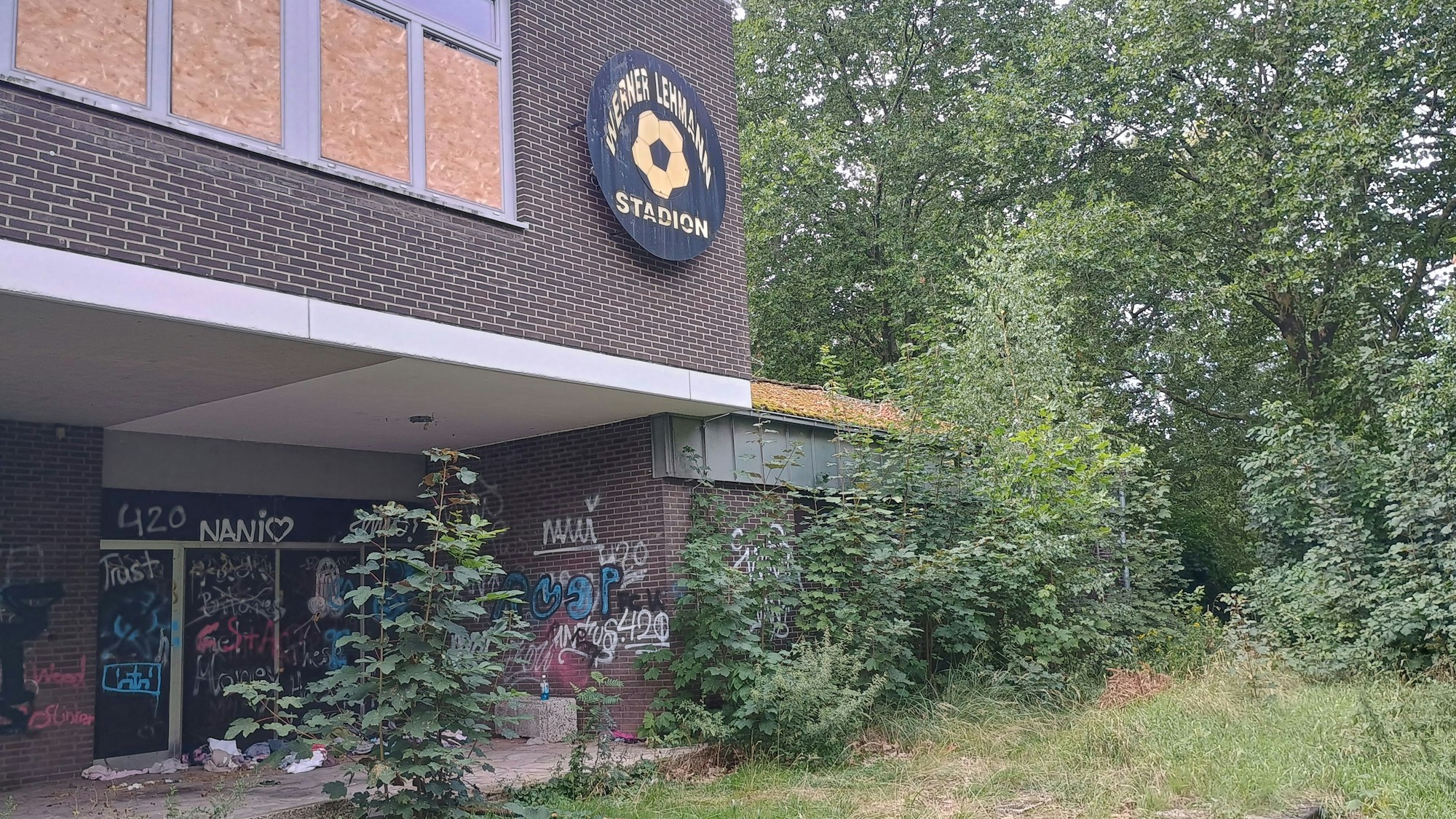 Die Pflanzen um das Gebäude wuchern. Ein Schild mit der Aufschrift „Werner Lehmann Stadion“ ist zu sehen.