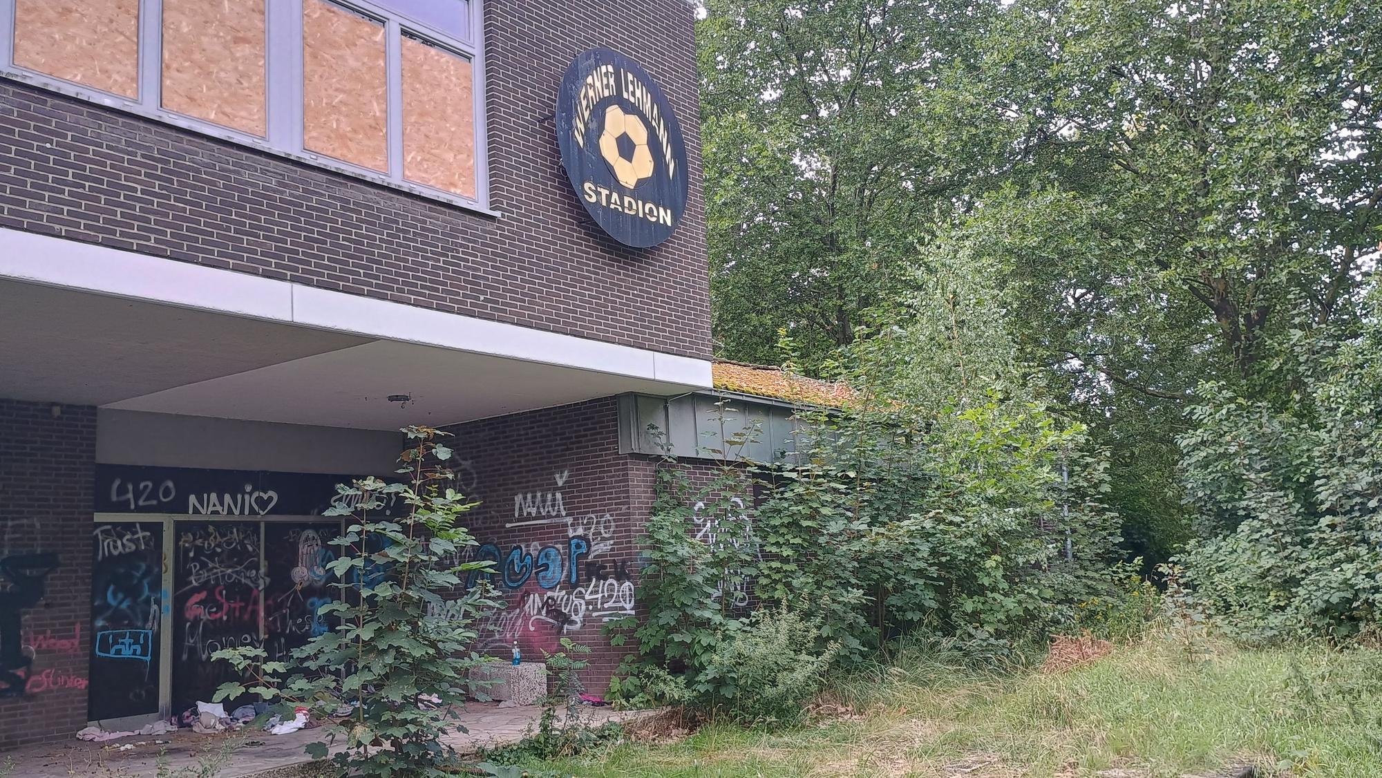 Die Pflanzen um das Gebäude wuchern. Ein Schild mit der Aufschrift „Werner Lehmann Stadion“ ist zu sehen.
