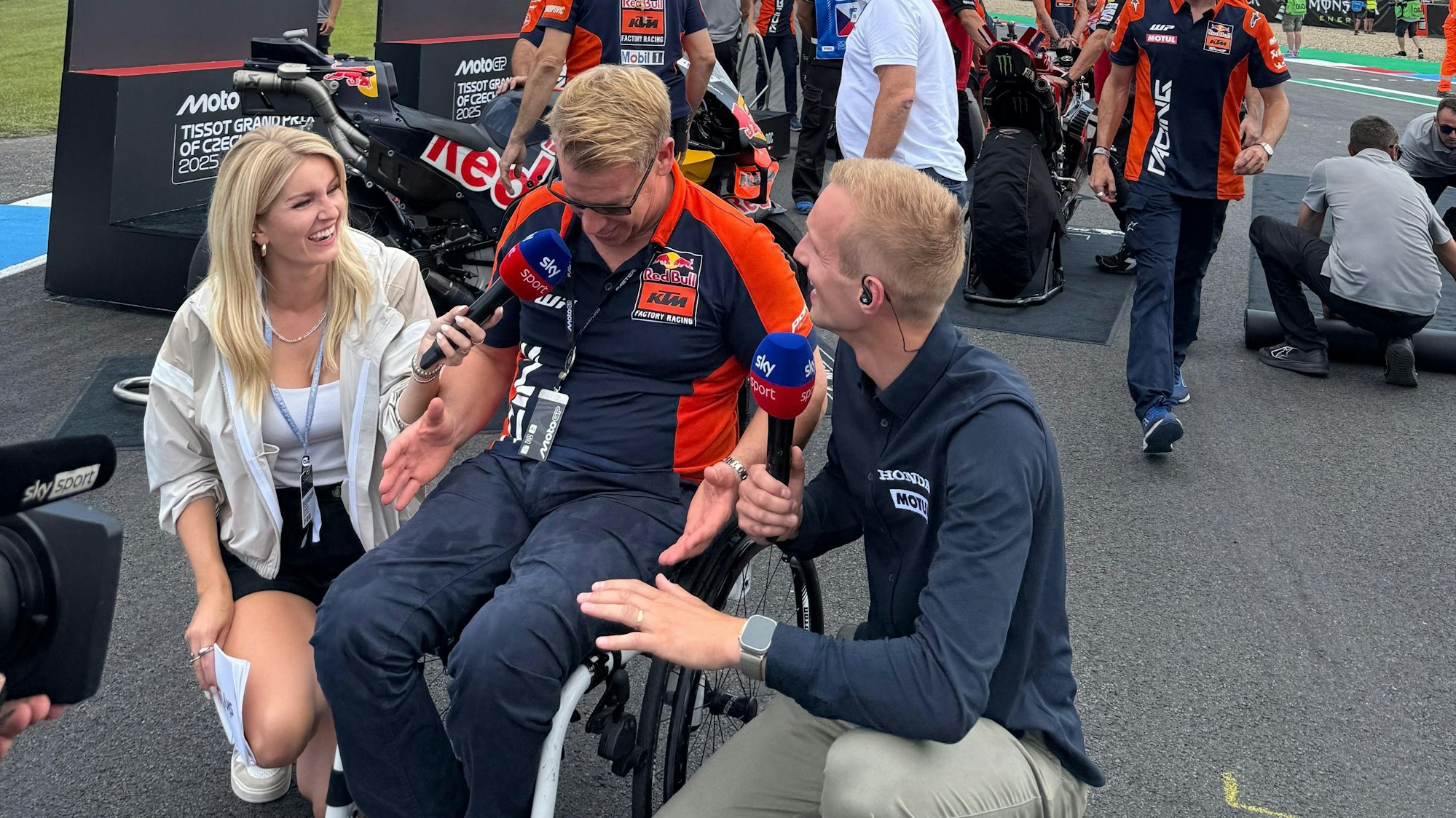 Eine Frau und ein Mann interviewen einen Mann im Rollstuhl.