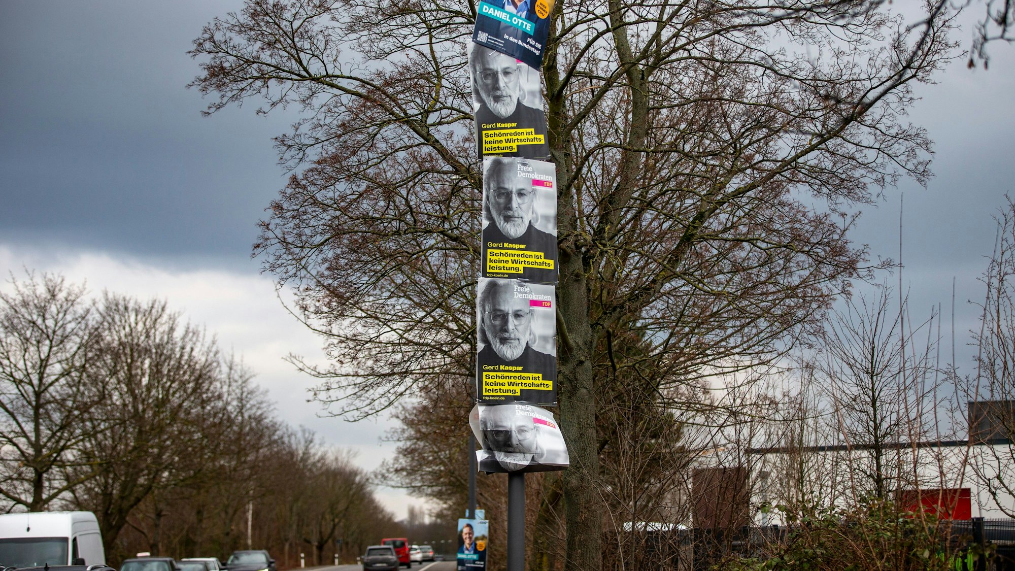 Plakate hängen übereinander an einem Laternenpfahl.