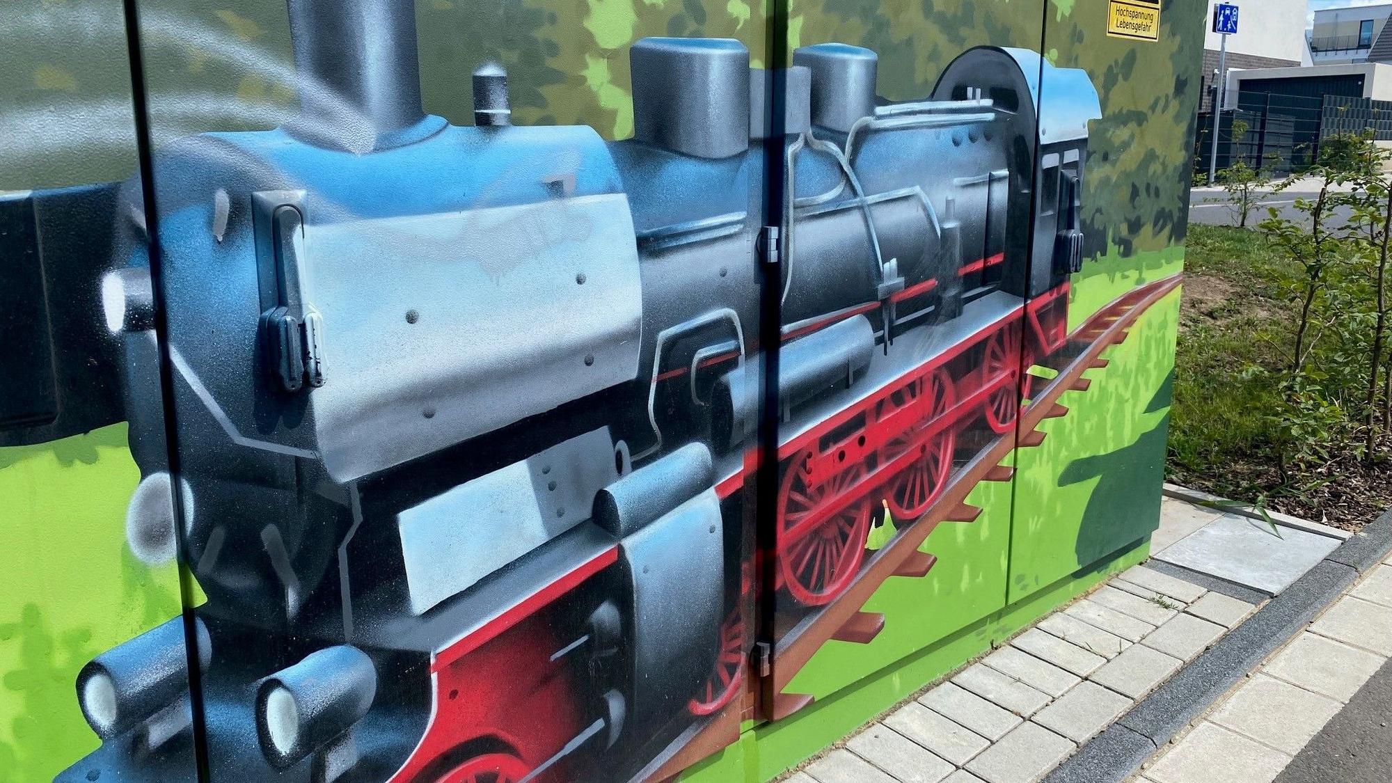 Einen bunt bemalten Stromkasten ziert eine Lokomotive.
