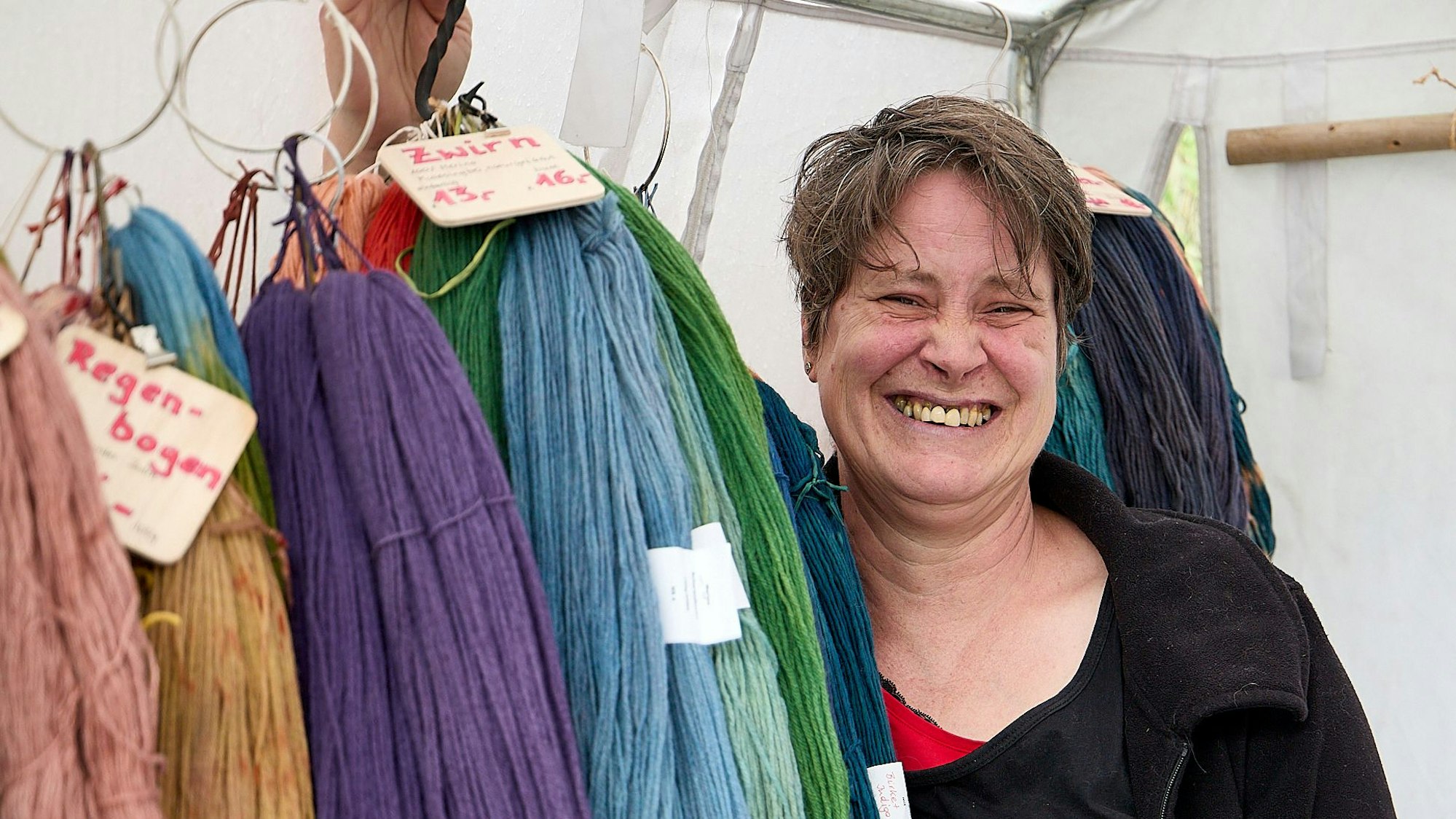Die Ausstellerin an einer Stange mit bunten Garnen.