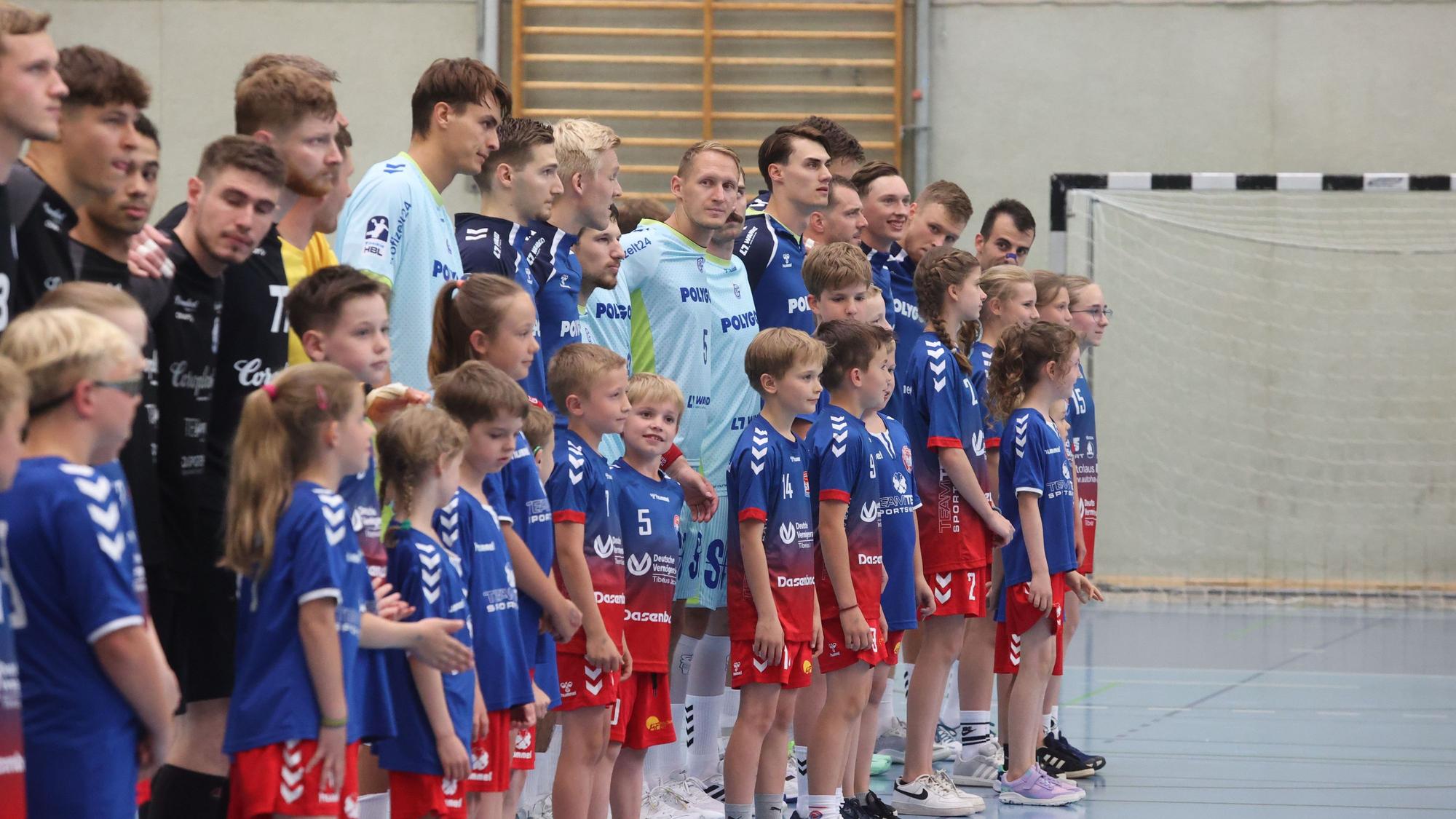 Kinder laufen mit Handball-Profis des VfL Gummersbach und des BHC bei einem Testspiel in Remscheid ein.