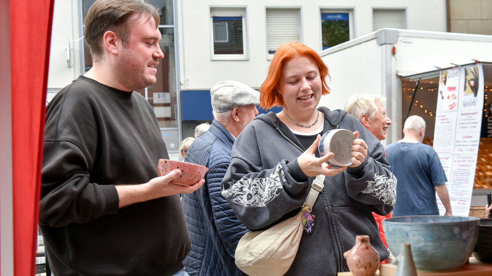 Eine Frau und ein Mann halten kleine Schalen aus Keramik in ihren Händen.