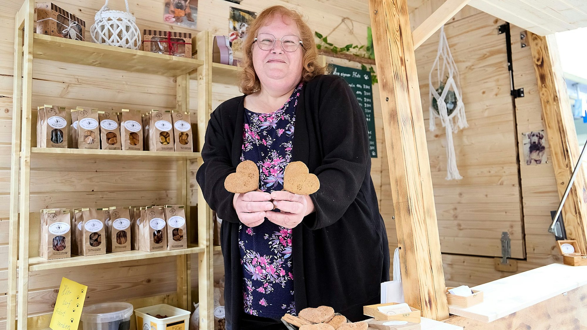 Die Ausstellerin hält an ihrem Stand zwei herzförmige Hundekekse in den Händen.