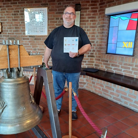 Diakon Michael Oschmann steht neben der Friedensglocke.