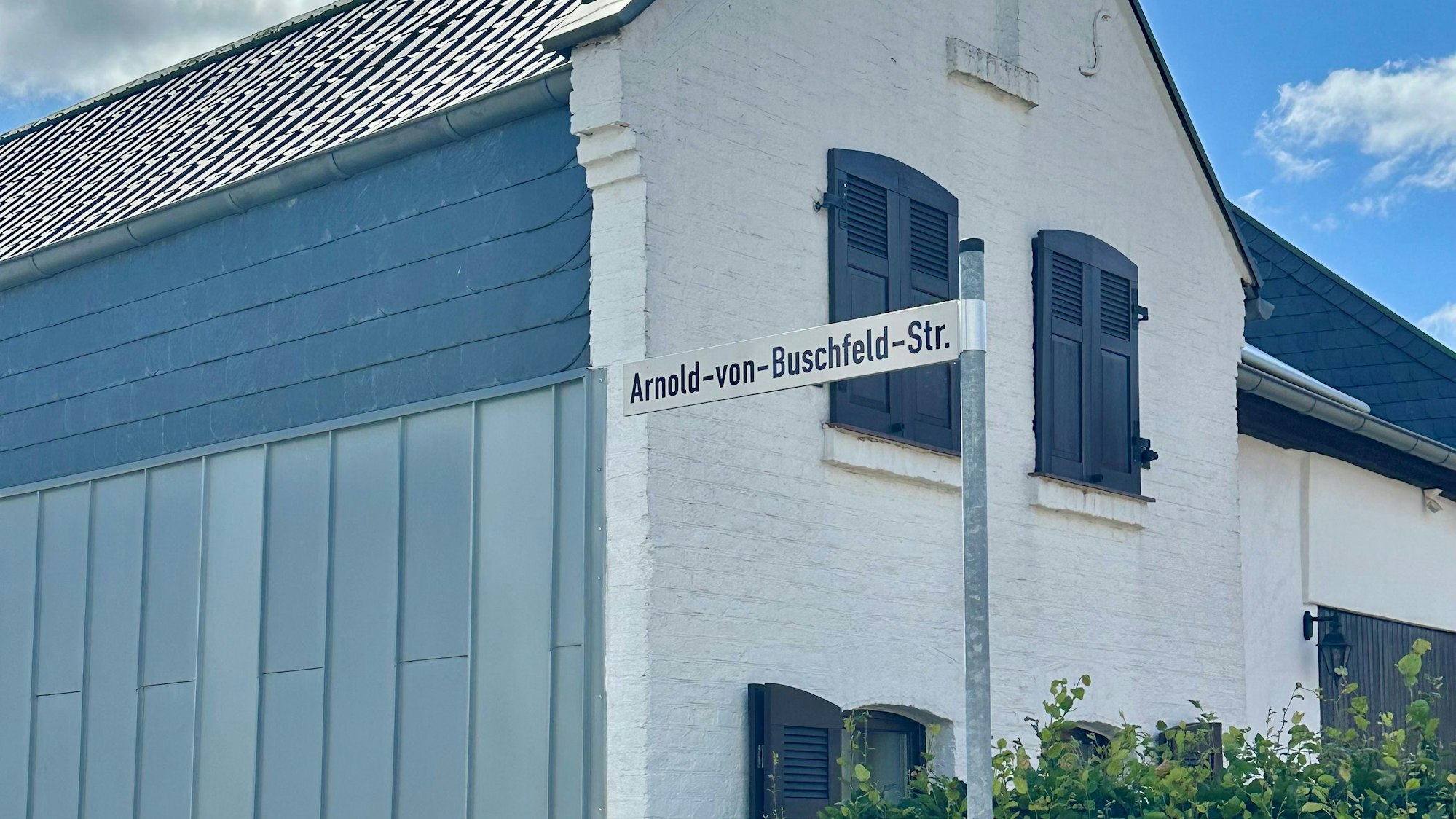 Zu sehen ist ein Straßenschild vor einem Haus.
