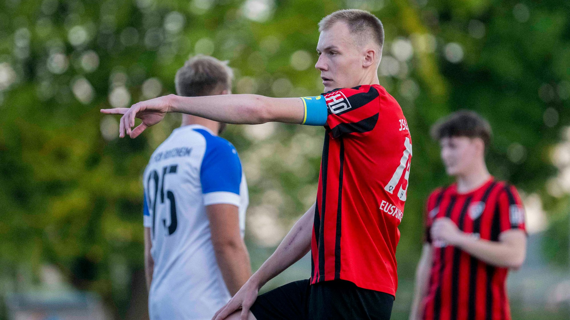 Luke Bungart zeigt mit dem linken Arm auf etwas. Er trägt eine blaue Kapitänsbinde.