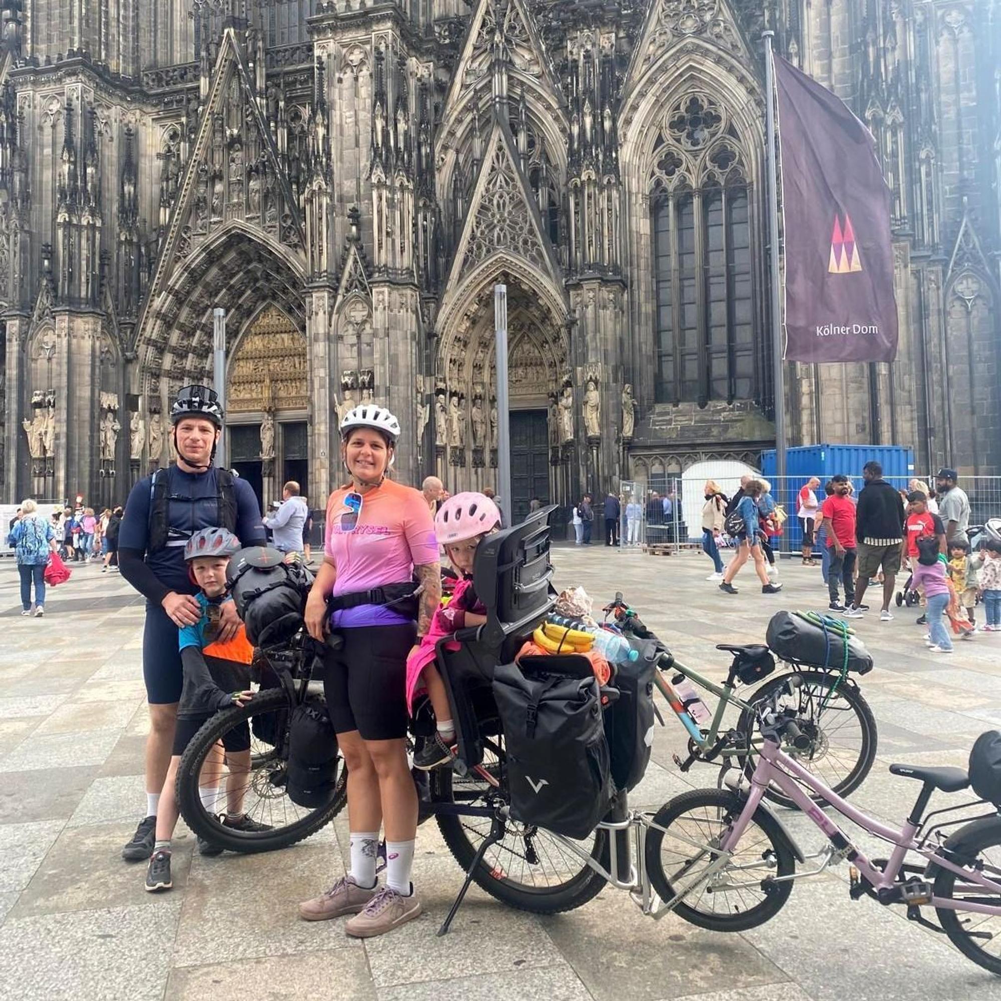 Lukas, Jakob, Sabrina und Paula Herr stehen mit ihren Fahrrädern vor dem Kölner Dom.