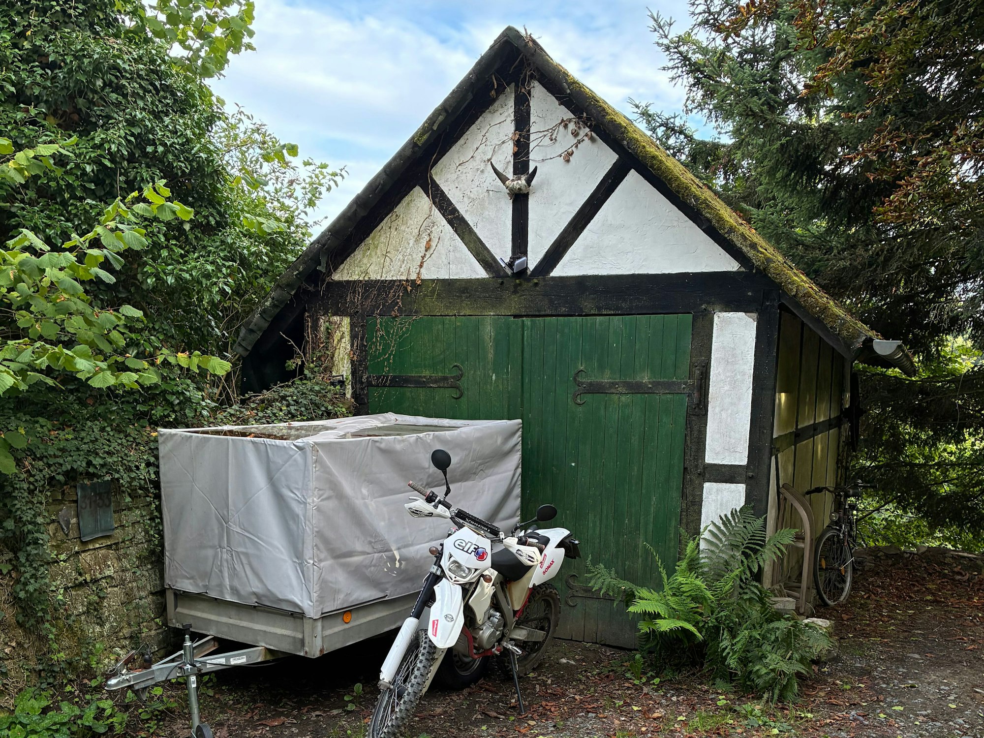 Vor der vermieteten Garage von Irmintraut Fuchs stehen ein Anhänger und ein Motorrad.