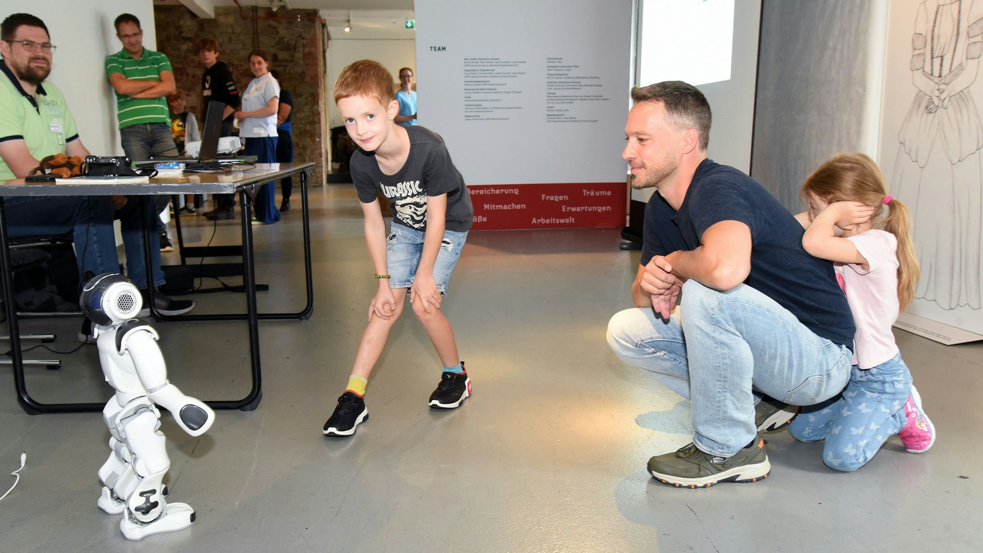 Während Ben (sieben Jahre) Roboter NAO interessiert betrachtet, sucht die fünfjährige Eveline lieber Rückendeckung bei ihrem Papa.
