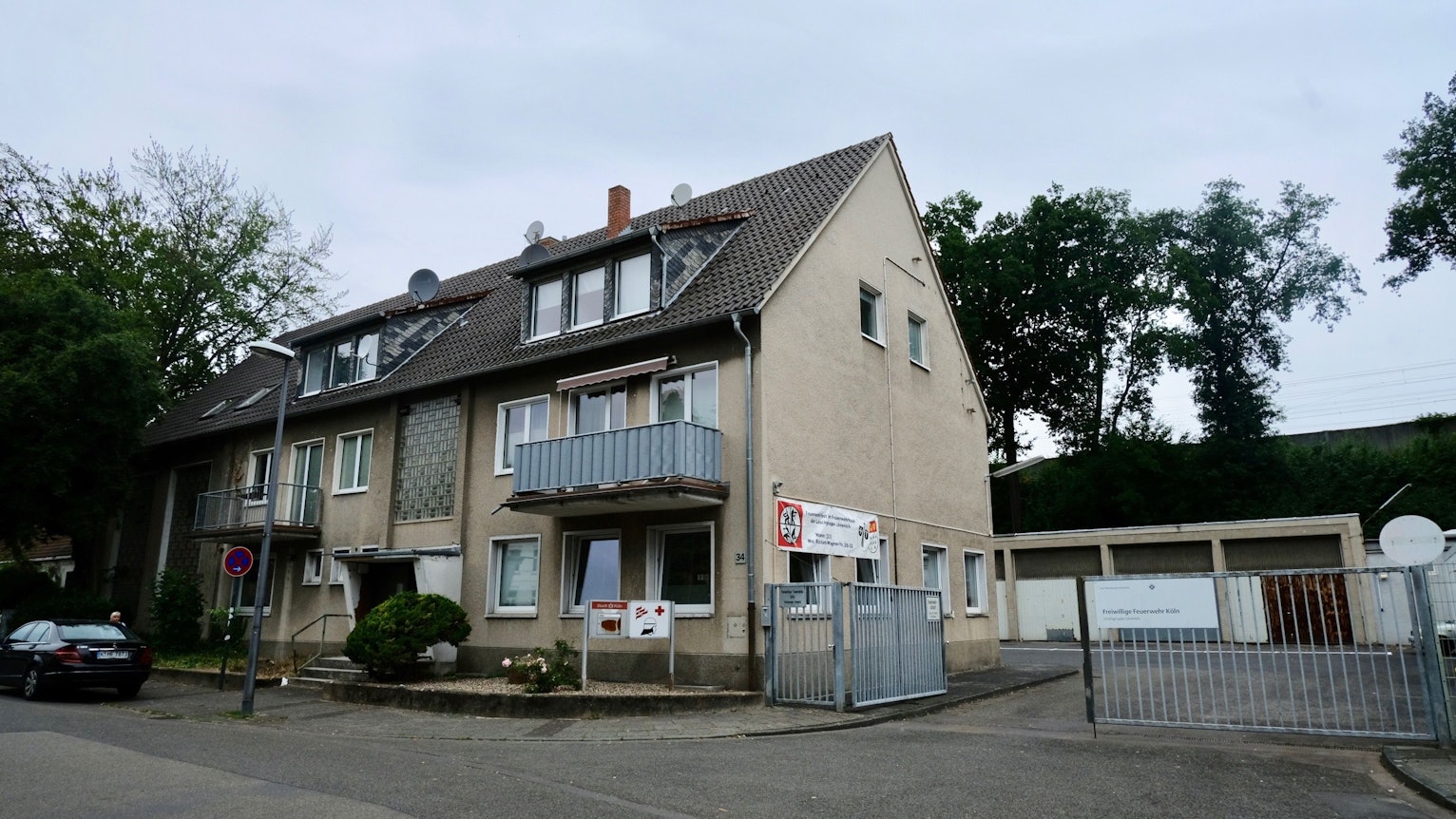 Ein Reihenhaus mit drei Stockwerken grenzt an einen großen Hof mit Garagen.