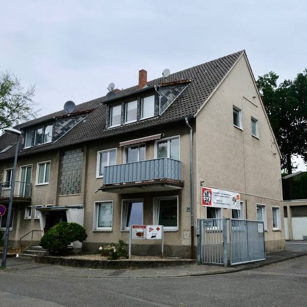 Ein Reihenhaus mit drei Stockwerken grenzt an einen großen Hof mit Garagen.
