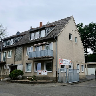 Ein Reihenhaus mit drei Stockwerken grenzt an einen großen Hof mit Garagen.