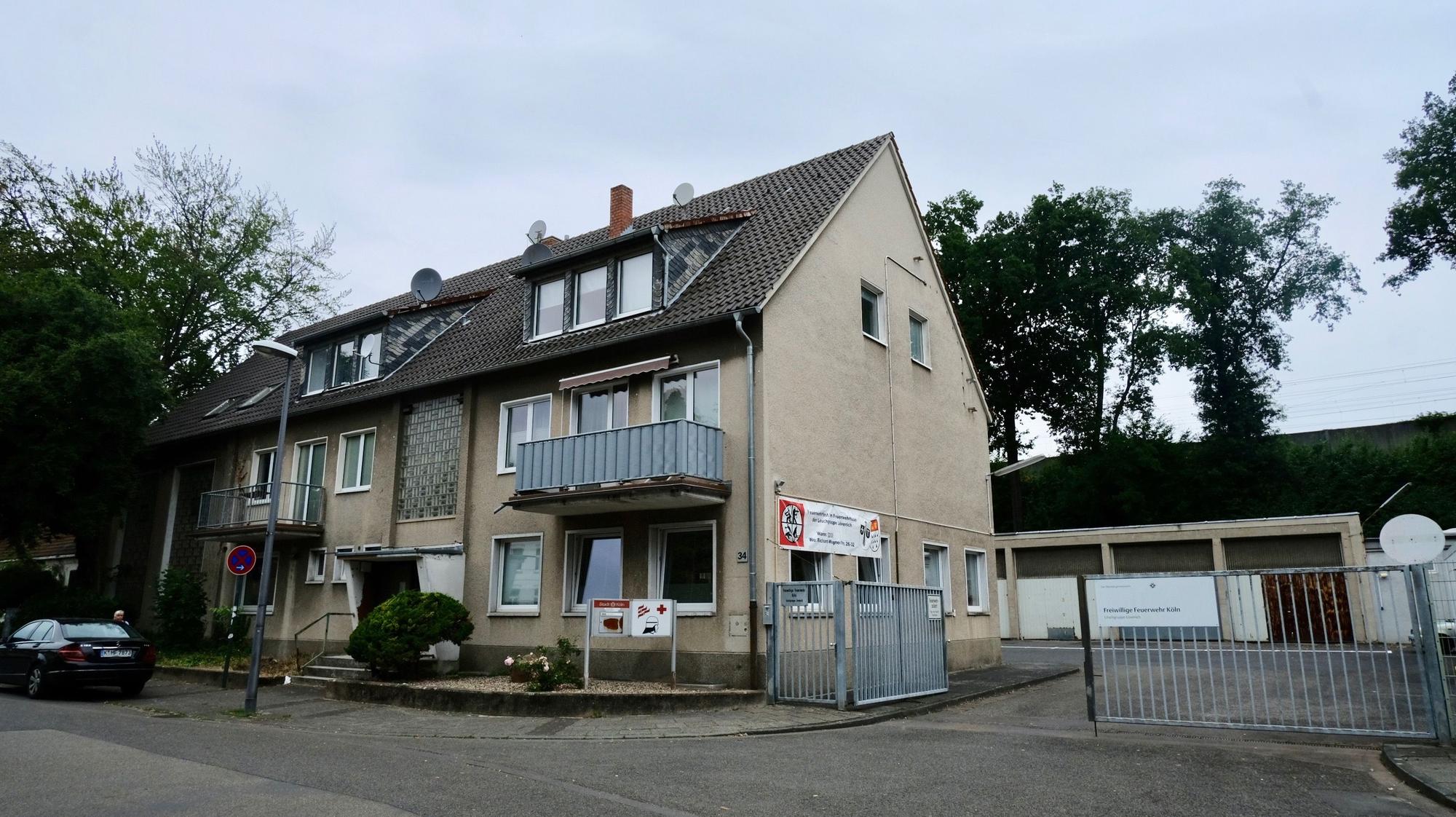 Ein Reihenhaus mit drei Stockwerken grenzt an einen großen Hof mit Garagen.