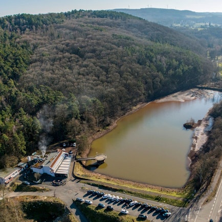 Eine Drohnenaufnahme des Mühlensees. Im Vordergrund stehen Autos auf einem Parkplatz.