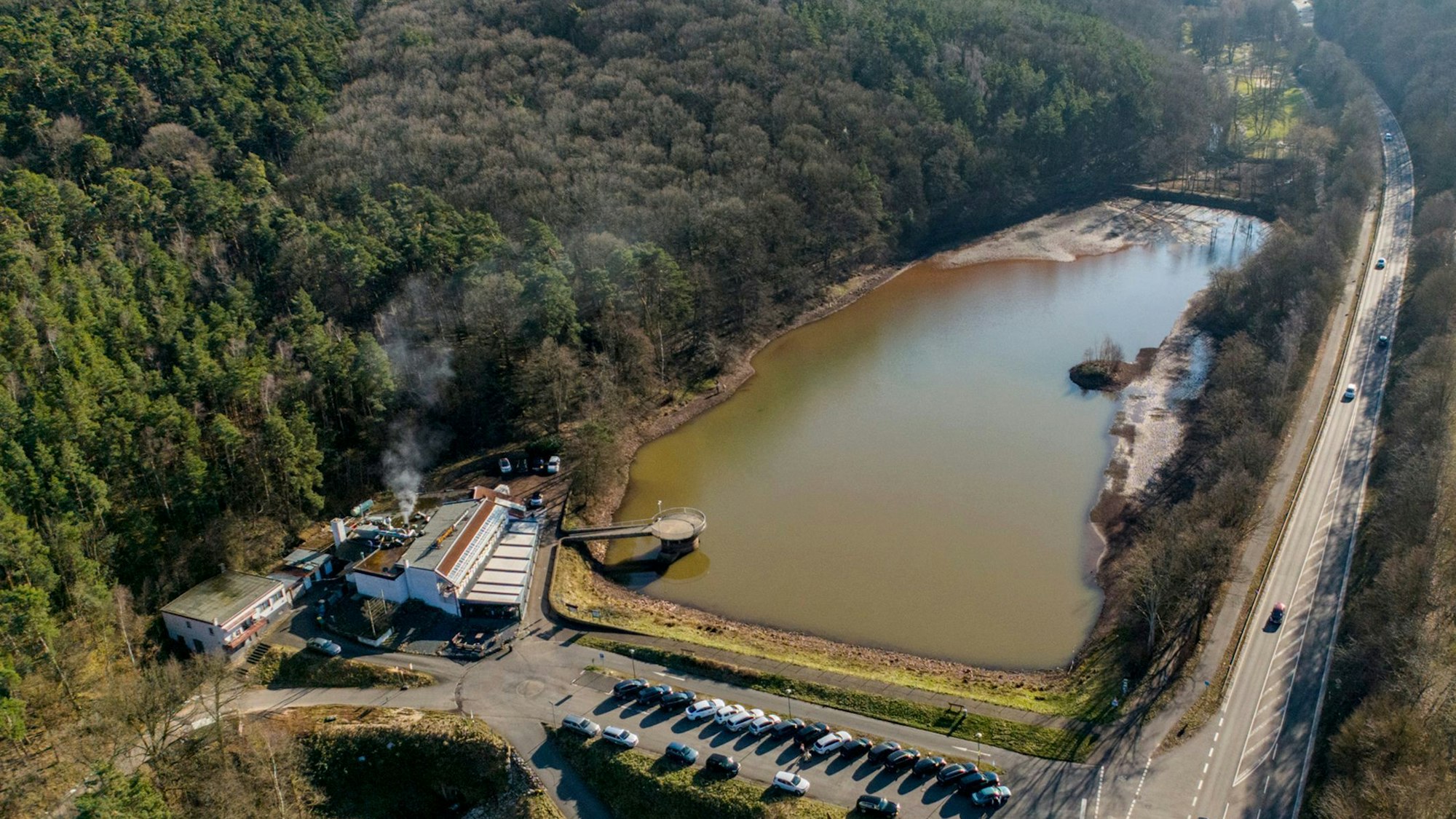 Eine Drohnenaufnahme des Mühlensees. Im Vordergrund stehen Autos auf einem Parkplatz.
