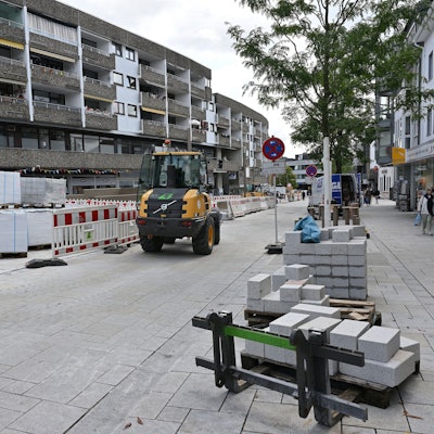 Ein Baufahrzeug fährt auf einem neu gepflasterten Straßenstück.