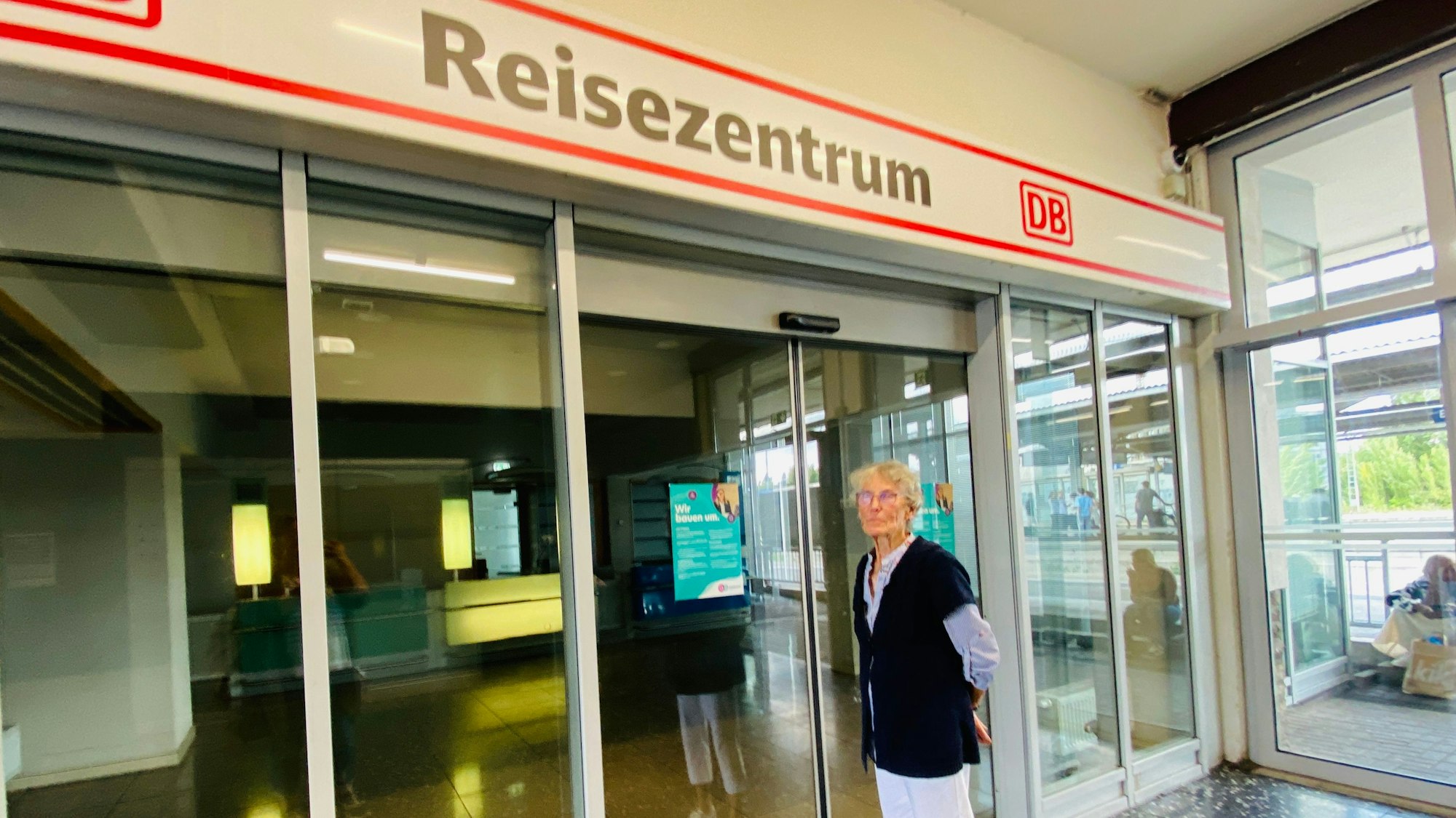 Elke Jahr steht vor dem leerstehenden, geschlossenen DB-Reisecenter. An der Tür hängt ein kleines Plakat.