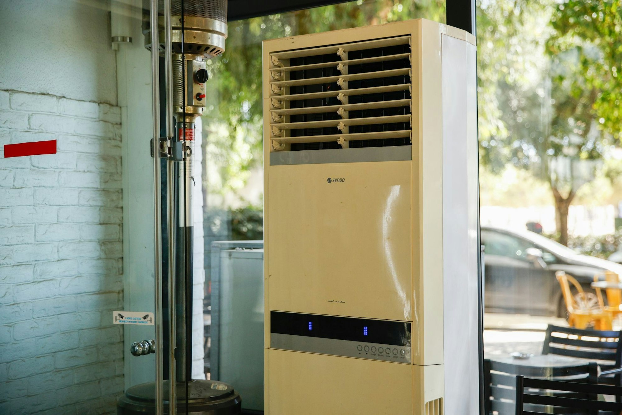 Athen: Eine mobile Klimaanlage steht im verglasten Innenraum eines Cafés. (Archivbild)