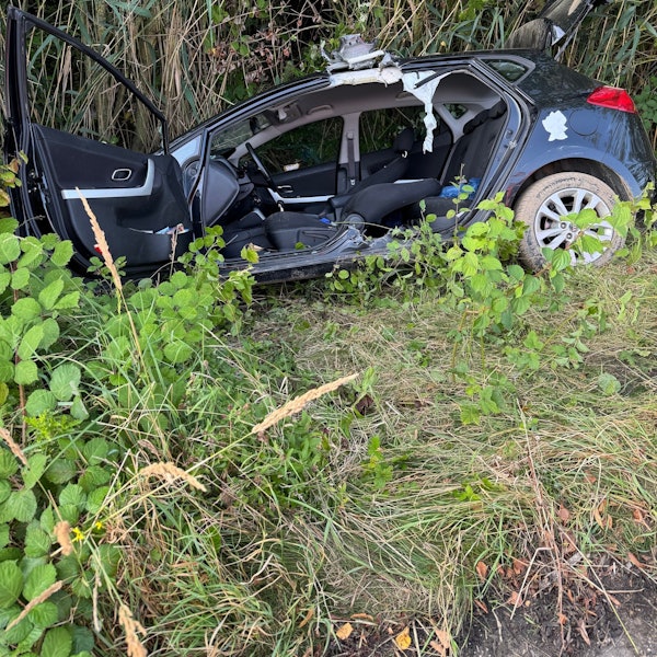 Das Bild zeigt einen Kleinwagen in einem Straßengraben.