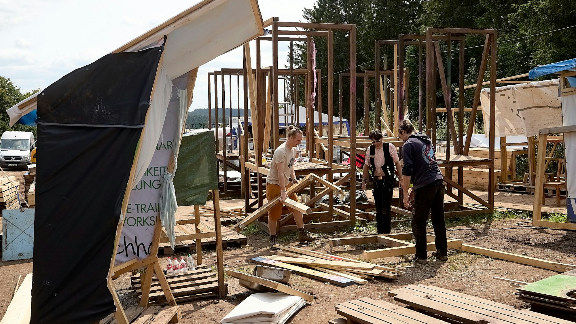 Drei Crew-Mitglieder bauen ein großes Holzbauwerk ab.