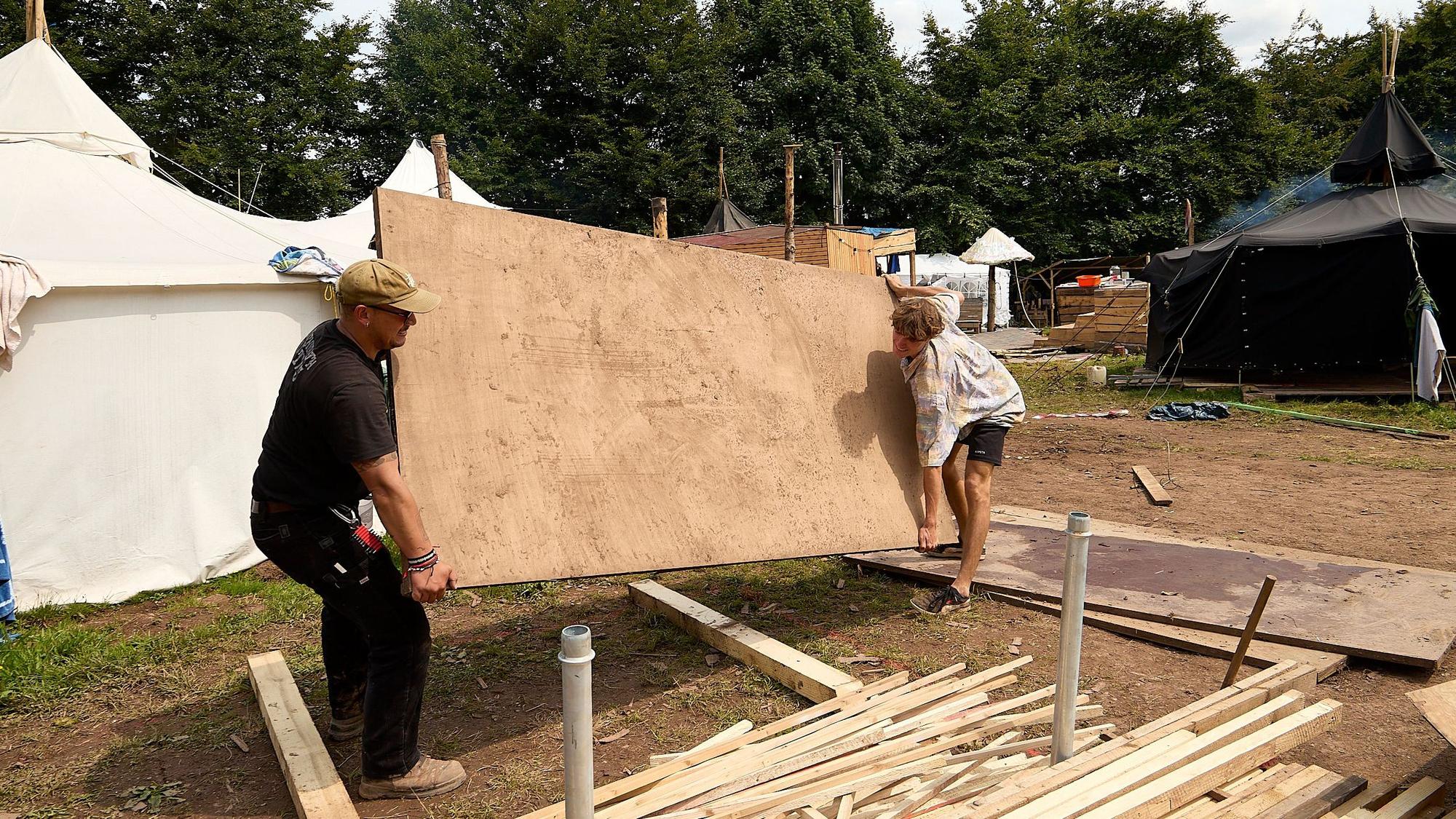Zwei Männer wuchten eine Holzplatte hoch.