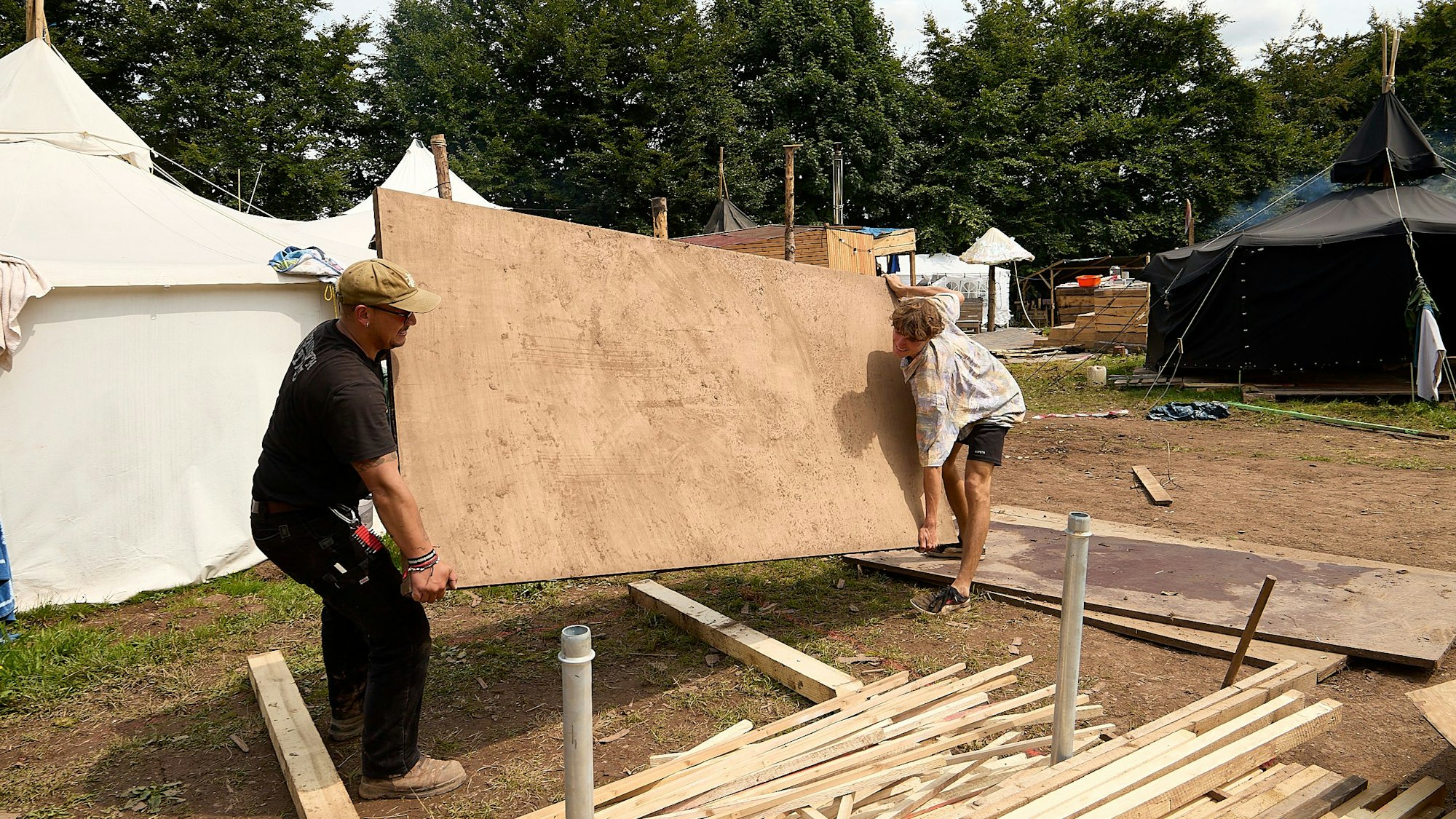 Zwei Männer wuchten eine Holzplatte hoch.