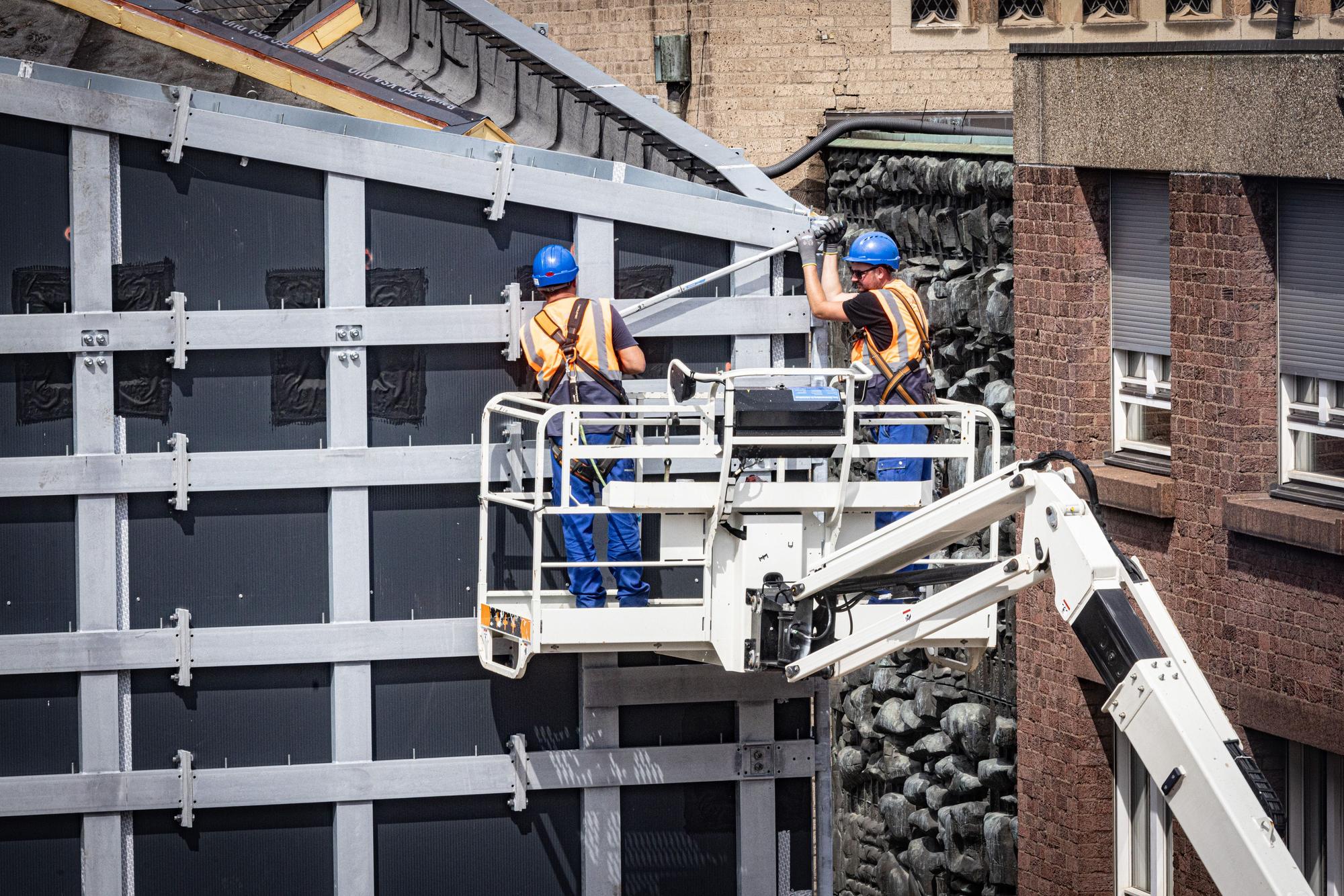 Handwerker arbeiten an der Fassade des MiQua.