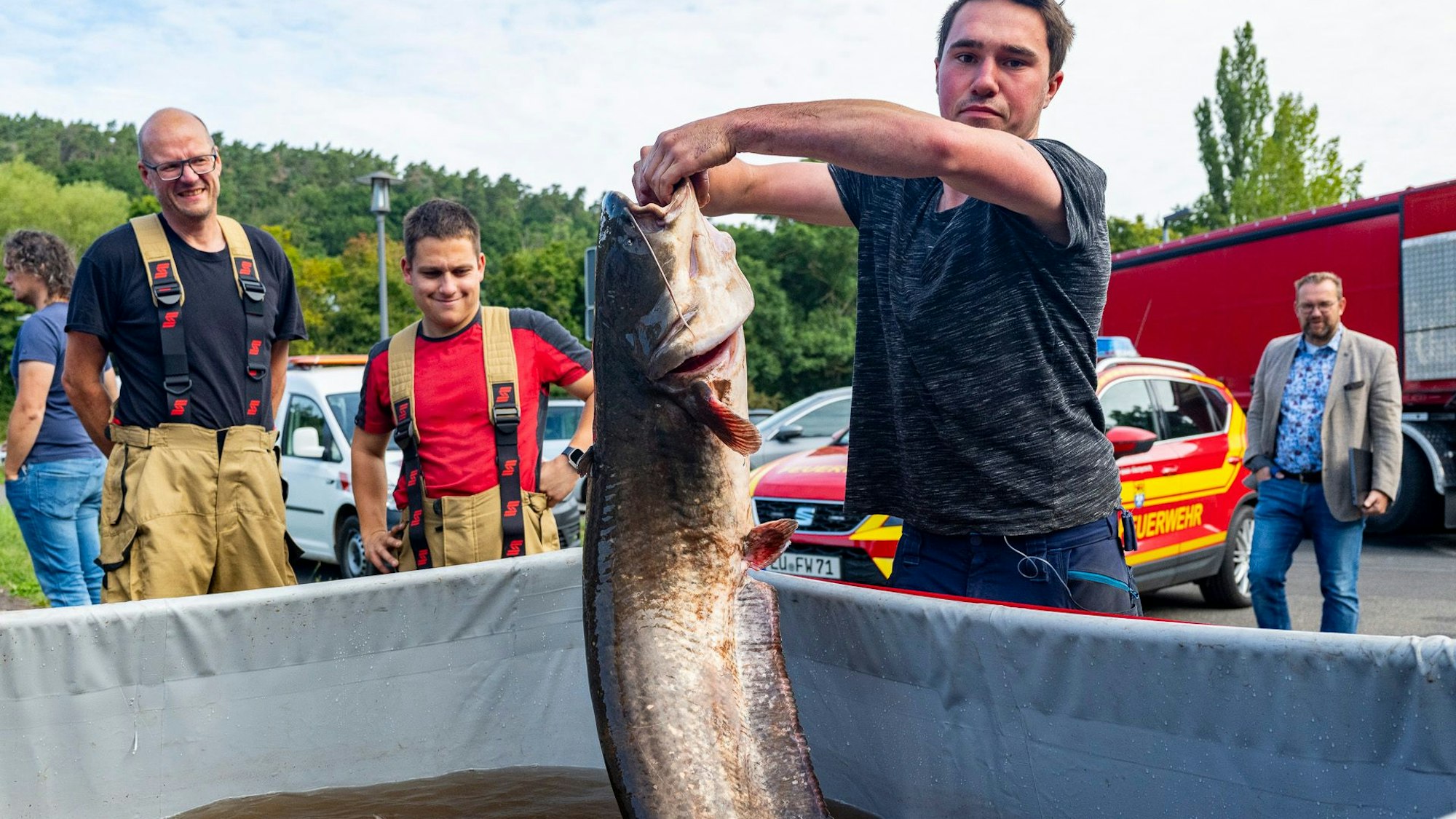 Das Bild zeigt Aaron Theis, der den Wels in die Kamera hält.