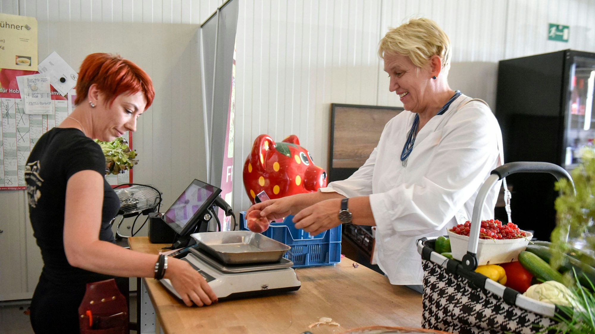 Das Foto zeigt eine Frau, die bei einer Verkäuferin etwas einkauft.