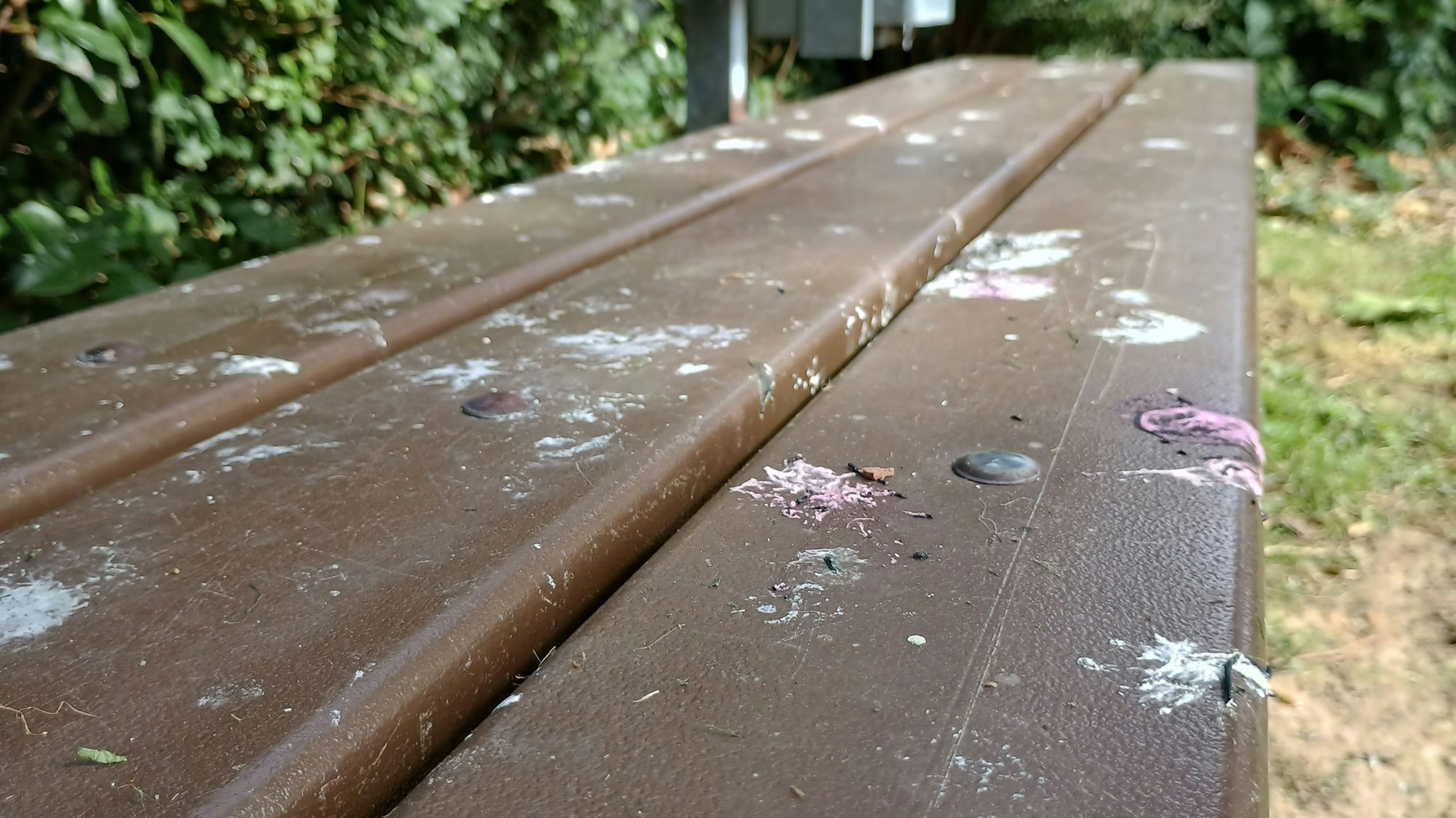 Das Bild zeigt die braune Bank, die von zahlreichen weißen Kotflecken beschmiert ist.