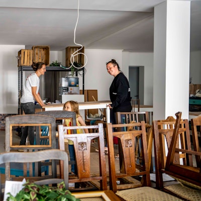 Das Bild zeigt Andrea Pick, die mit ihrer Frau Julia einen Tisch trägt.