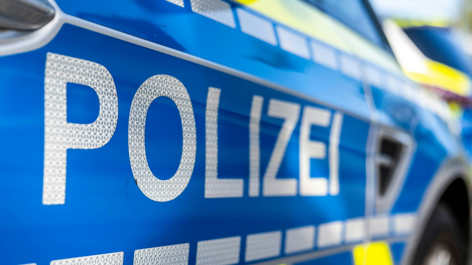 An der Tür von einem Streifenwagen steht der Schriftzug „Polizei“. (Symbolbild)
