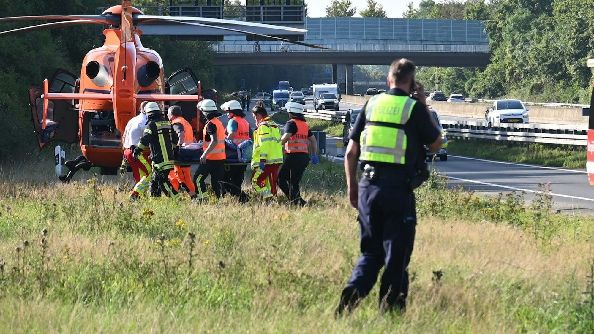 Das Bild zeigt Einsatzkräfte der Feuerwehr, die einen schwerverletzten Mann in den Rettungshubschrauber tragen.