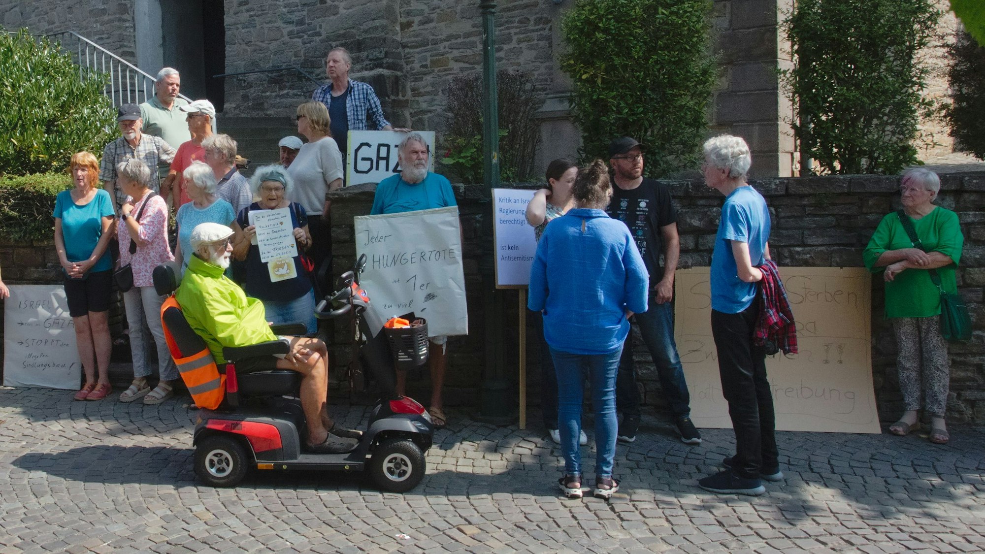Einige Menschen stehen mit selbstgemachten Plakaten vor der Kirche in Lindlar.