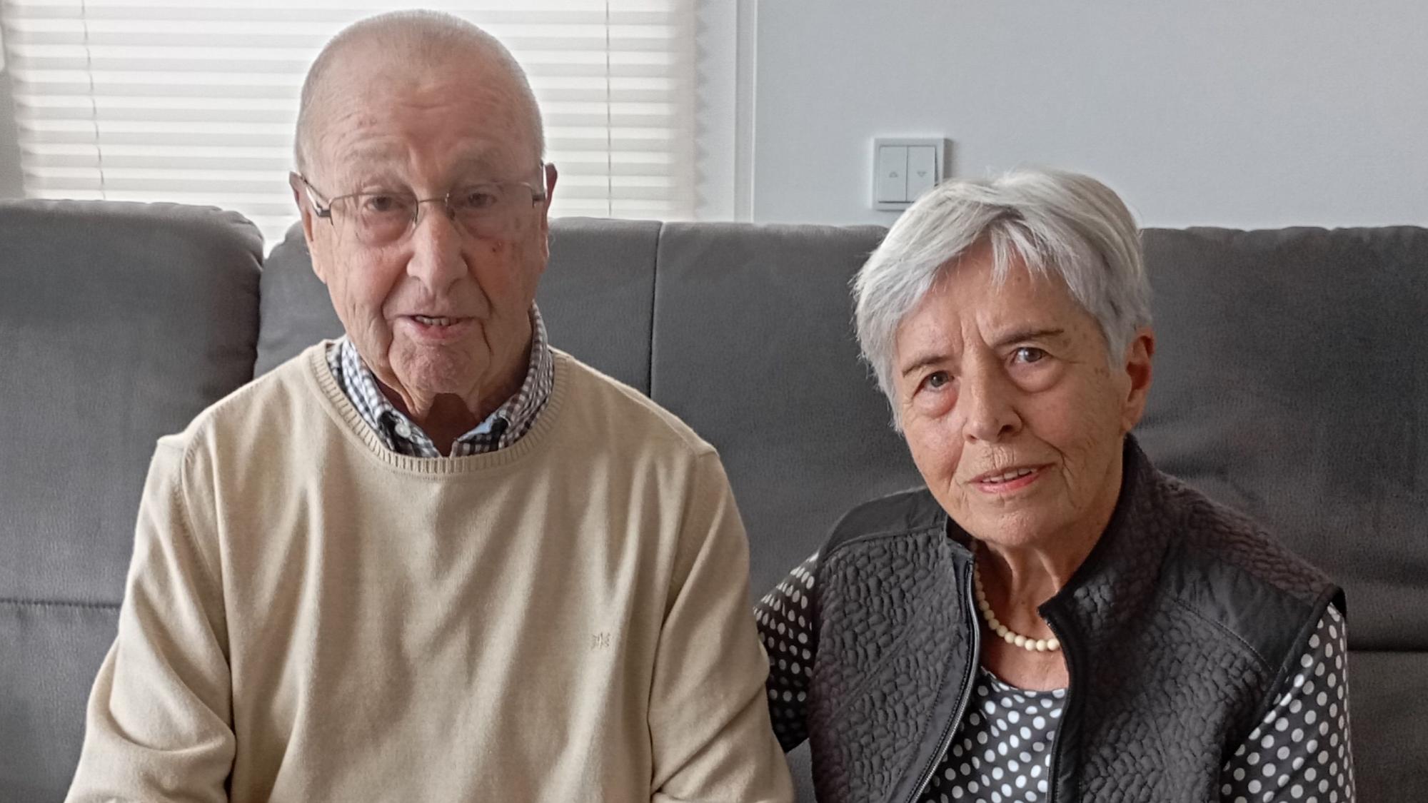 Die beiden sitzen auf einem Sofa. Ingeborg Schulte legt den Arm auf den Rücken ihres Mannes .