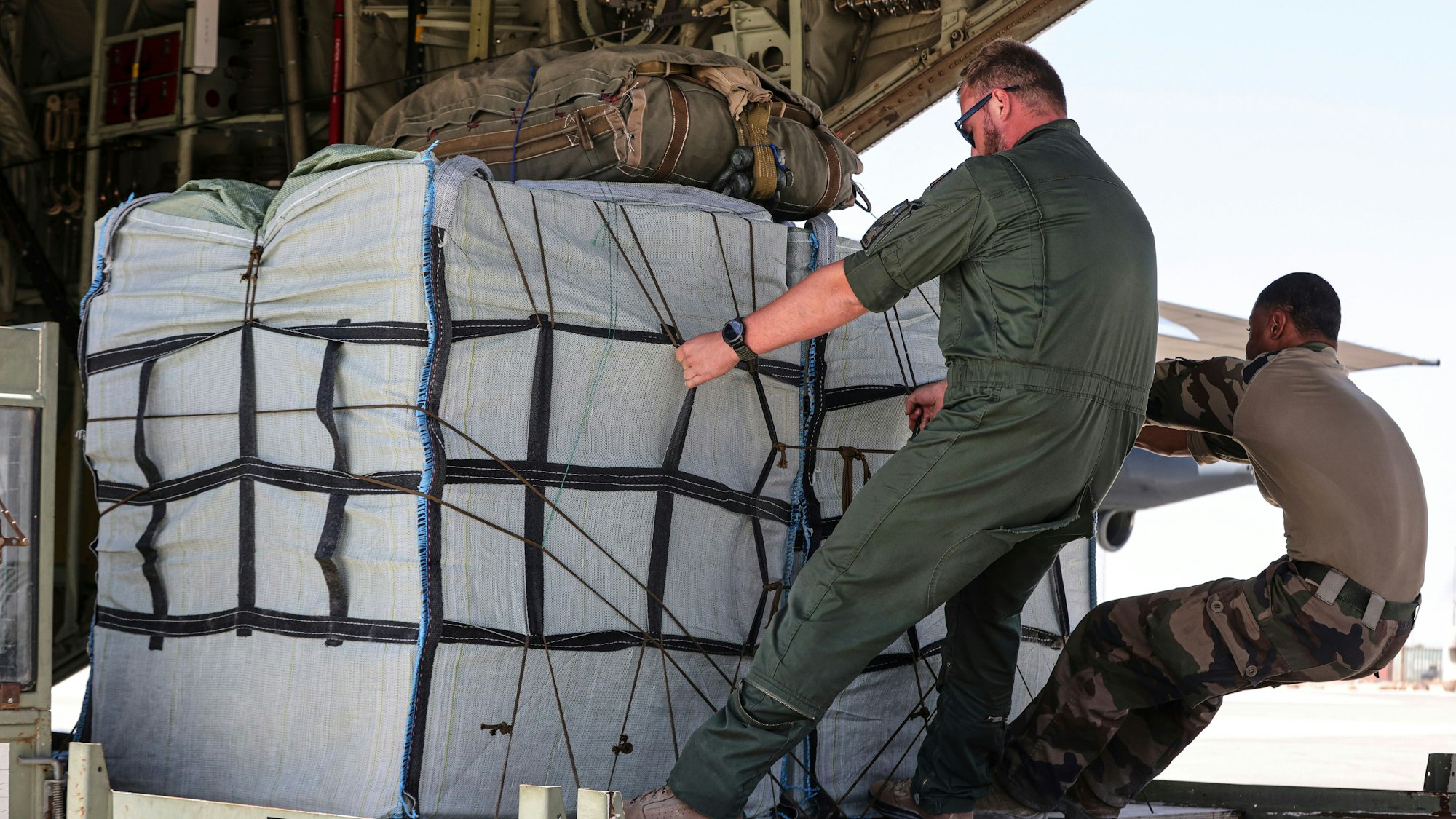 Angehörige der französischen Luftwaffe beladen ein Flugzeug vom Typ C-130 mit Containern für humanitäre Hilfe, die über dem Gazastreifen abgeworfen werden sollen.