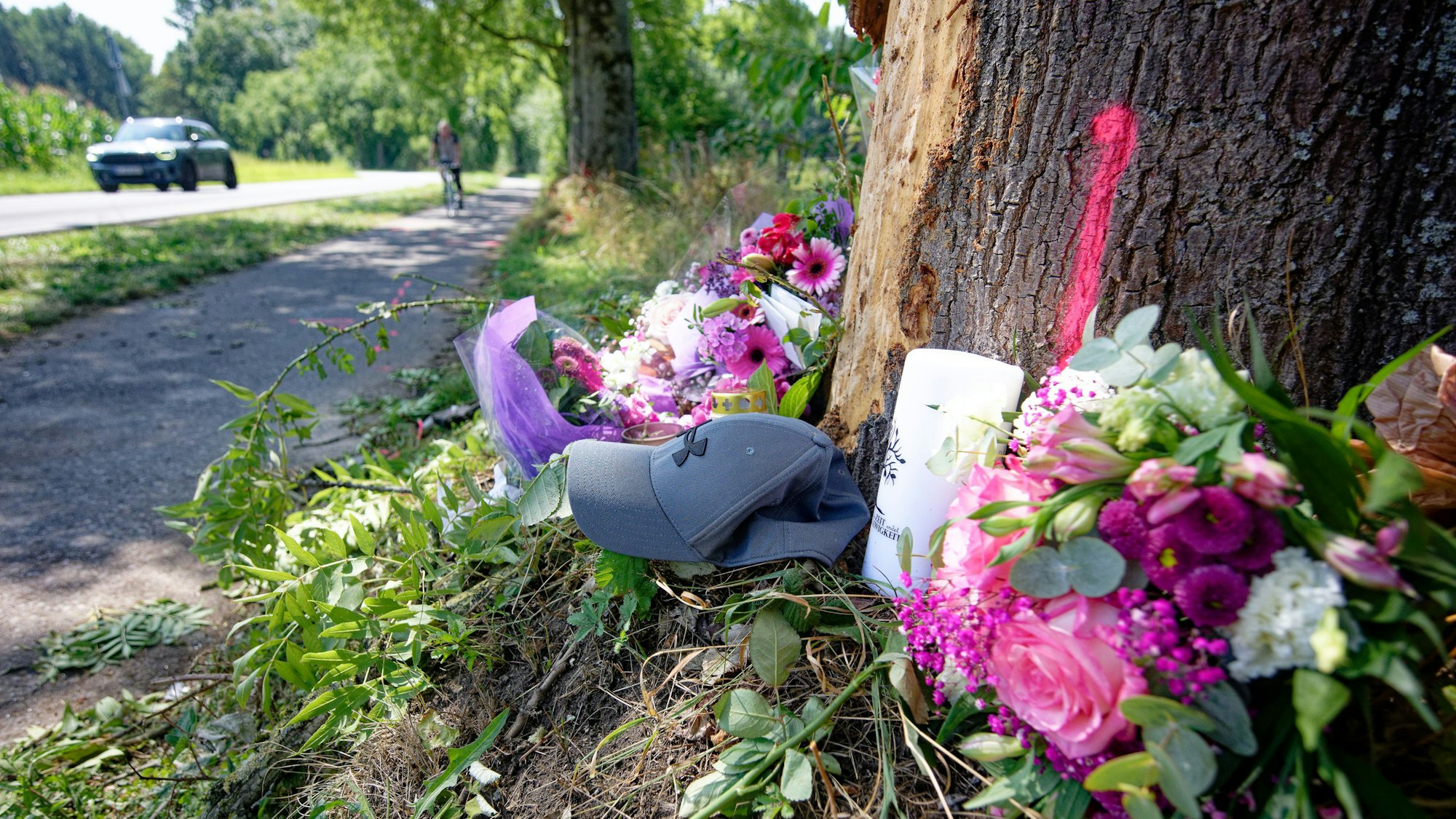 10.08.2025, Nordrhein-Westfalen, Monheim: Blumen, Kerzen und eine Mütze liegen an einer Unfallstelle zwischen Monheim und Düsseldorf. Bei dem Unfall verstarben ein 15-Jährige und eine 17-Jährige. Drei weitere Insassen den Unfallfahrzeuges wurden schwer verletzt. Foto: Henning Kaiser/dpa +++ dpa-Bildfunk +++