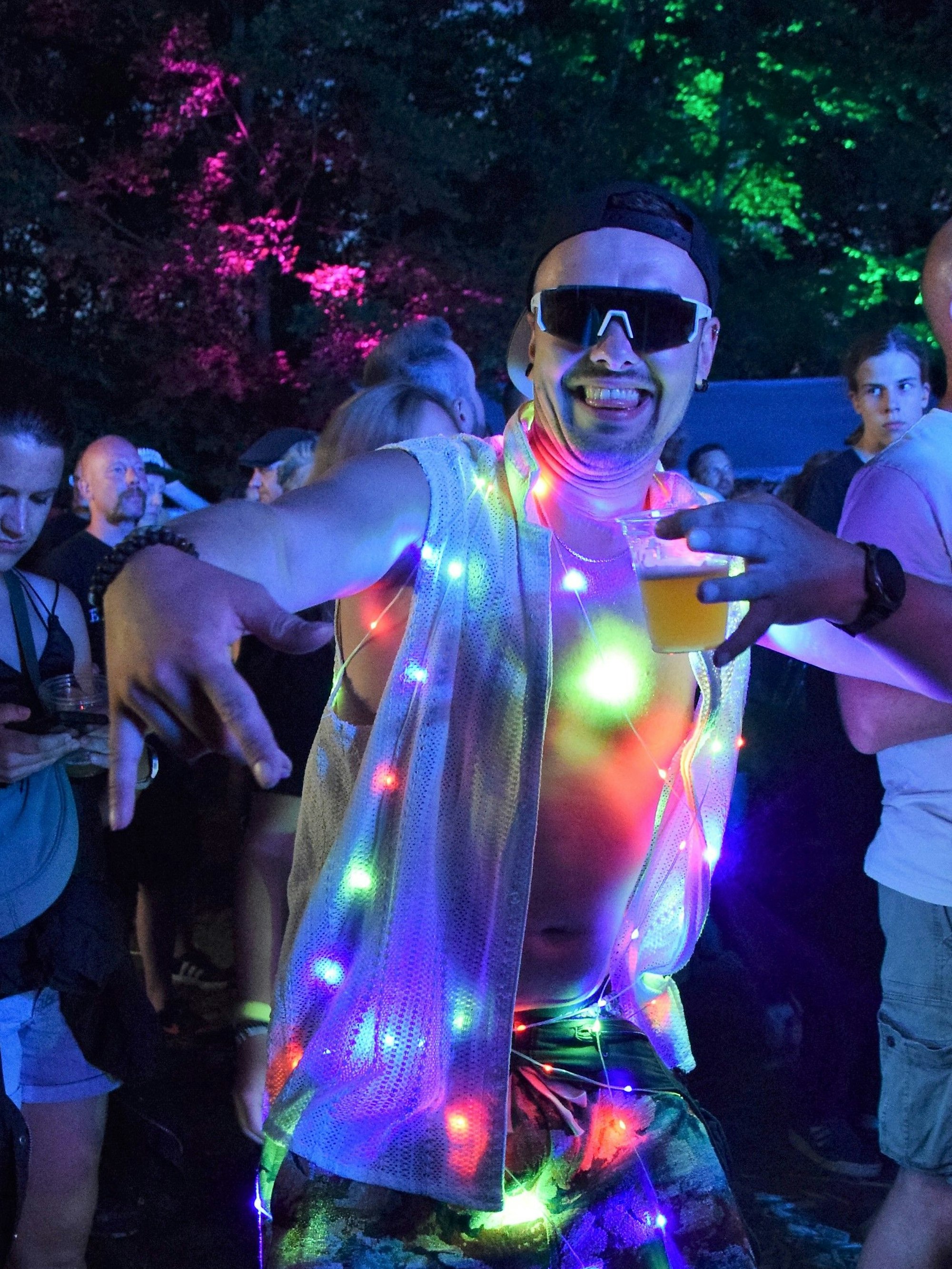 Das Bild zeigt einen tanzenden Besucher des Trafo-Festivals mit leuchtender Kleidung.