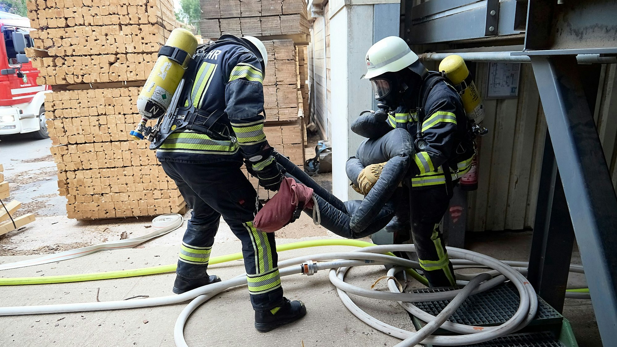 Zwei Feuerwehrleute tragen gemeinsam eine der großen und schweren Übungspuppen.