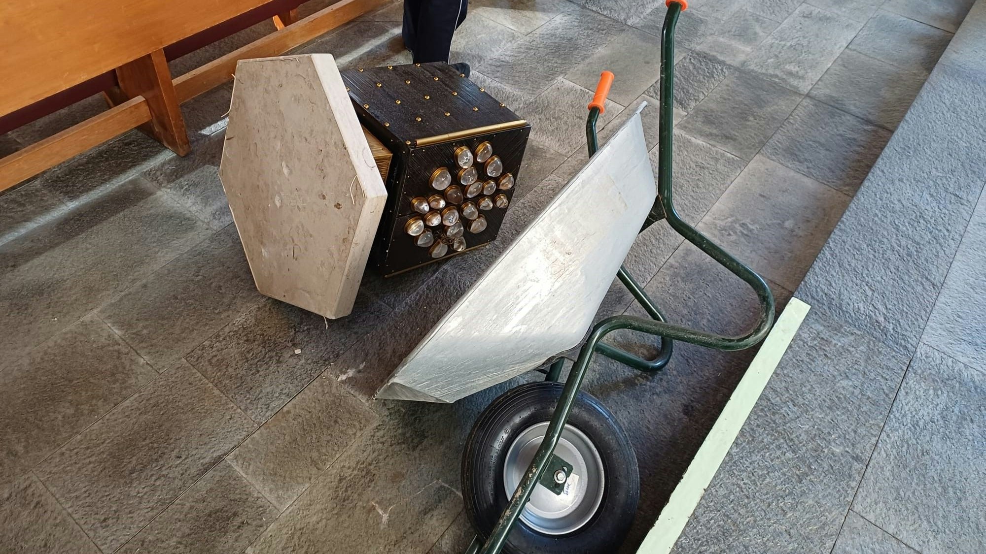Neben einer umgekippten Schubkarre liegt ein Tabernakel auf dem Boden.