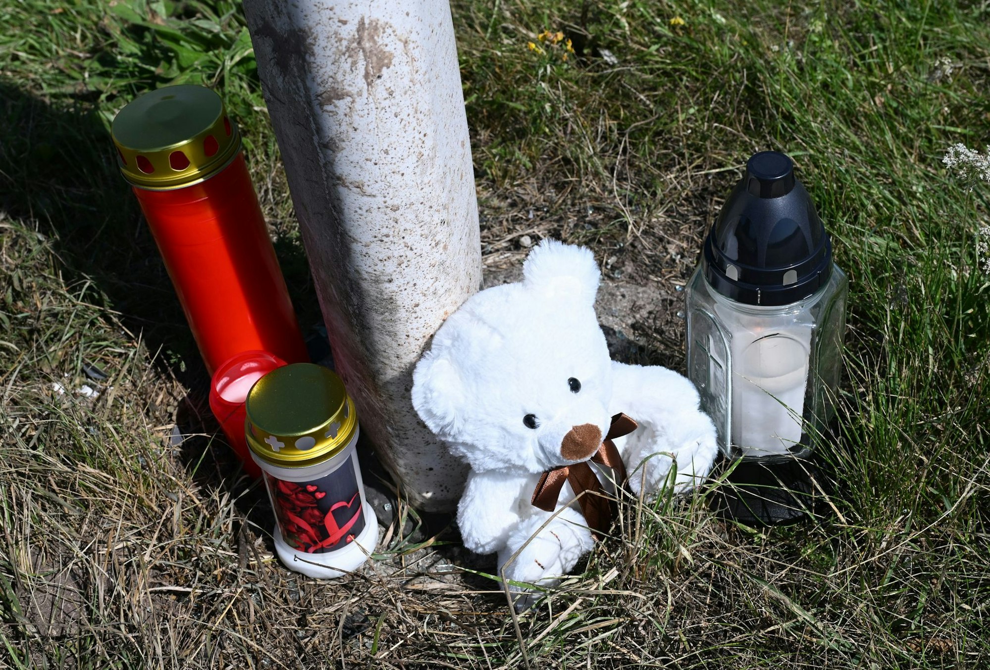 Menschen haben Kerzen und einen Teddybären an der Unfallstelle abgestellt.
