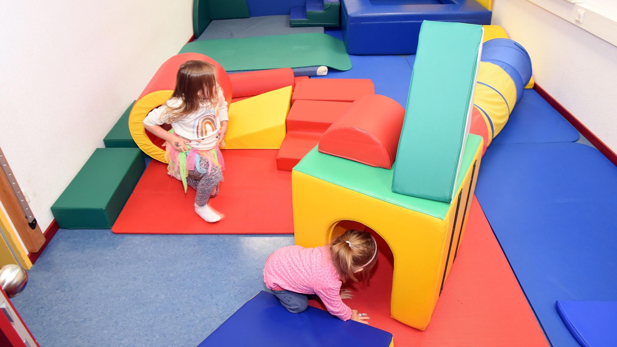 Zwei Kinder spielen auf bunten Matten.
